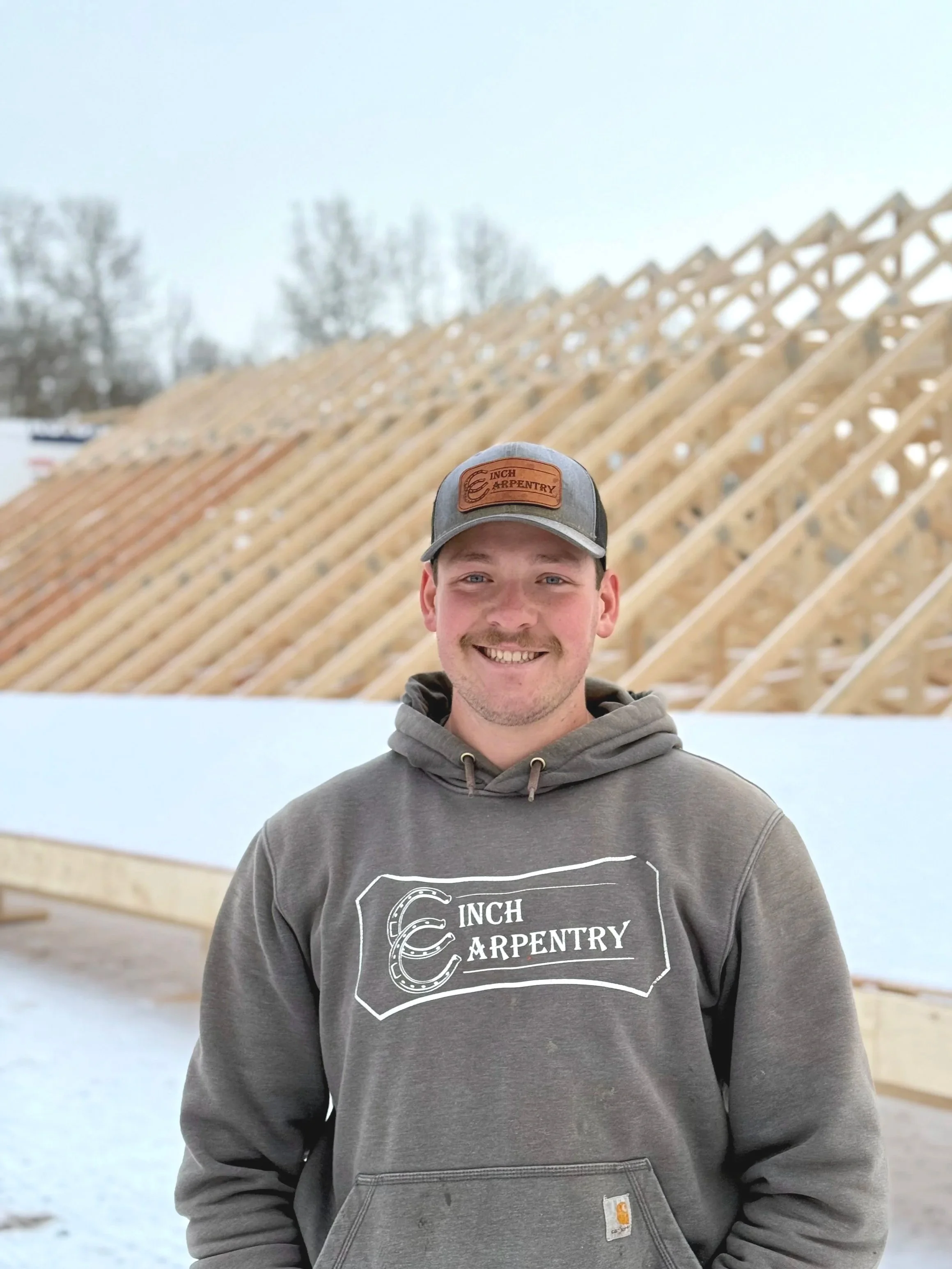 Five men standing together in a laser tag arena, smiling and holding laser tag guns. They are wearing casual clothing and hats, with a dark background adorned with colorful string lights, and a sign that reads #HITZHATCHETS at the top.