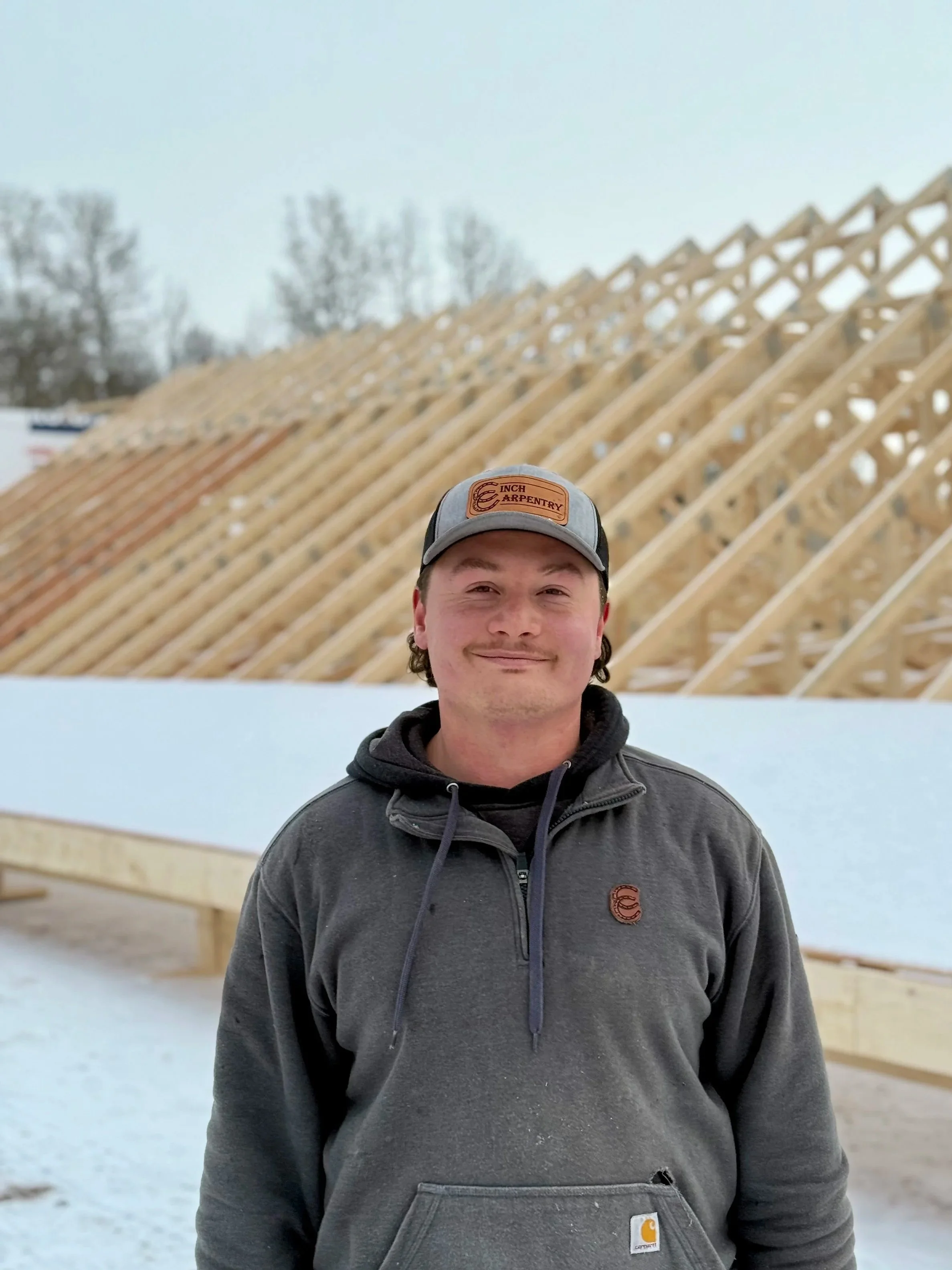 Five young men standing together on a stage, smiling with some holding tools like hammers. The stage background is made of wood with colorful lights overhead and a hashtag '#HITZHATCHETS' projected on the top. They appear to be participating in an activity or event related to using hammers.