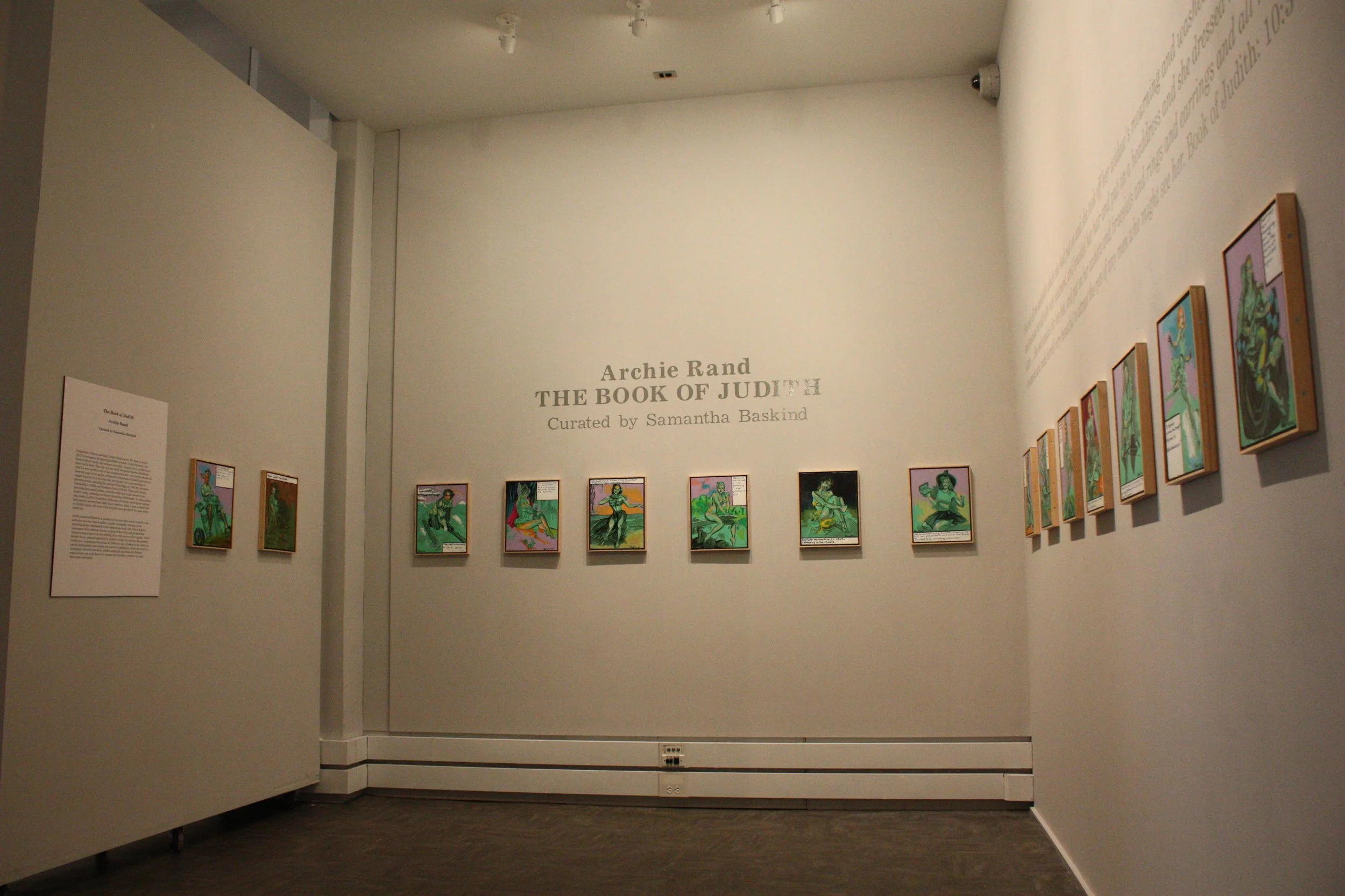 Gallery exhibit titled "The Book of Judith" by Archie Rand, curated by Samantha Baskind, displaying multiple colorful art pieces on a white wall.