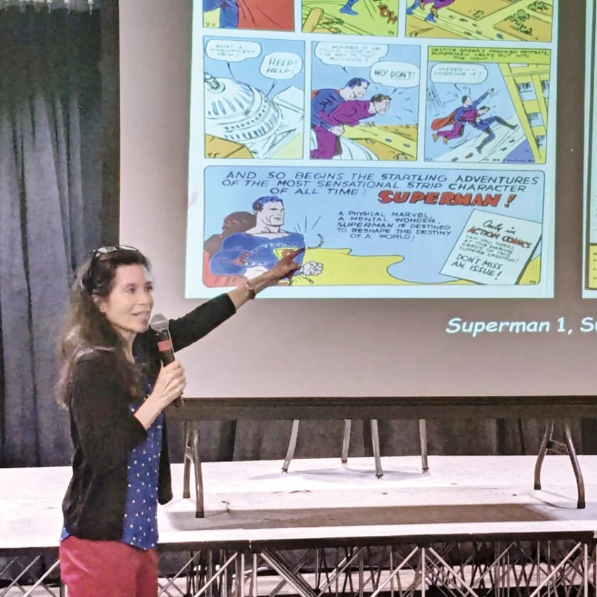 Samantha Baskind, lecturing on a presentation slide about Superman comic books.