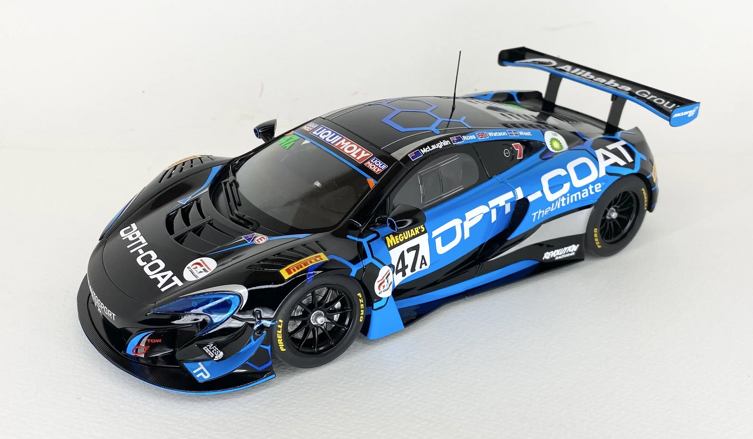 Scale model of a racing car with a black and blue design, featuring sponsor logos and the number 47A, on a white surface.