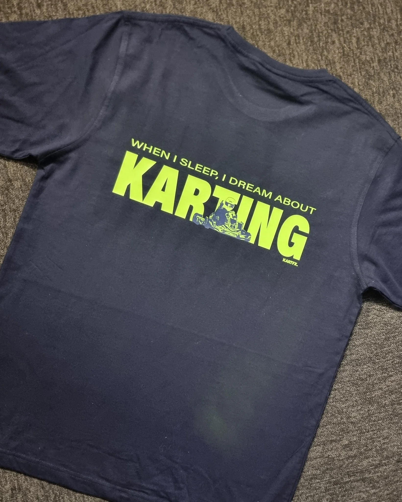 A navy blue T-shirt with lime green text that says 'When I sleep, I dream about Karting' and an illustration of a person driving a go-kart.