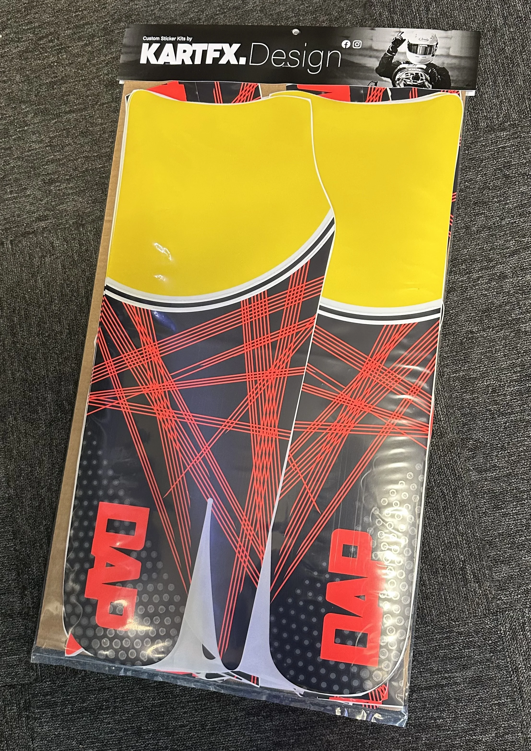 Packaging of two kart racing stickers with red and black design, yellow top sections, and the word 'DAD' in red letters on the bottom.
