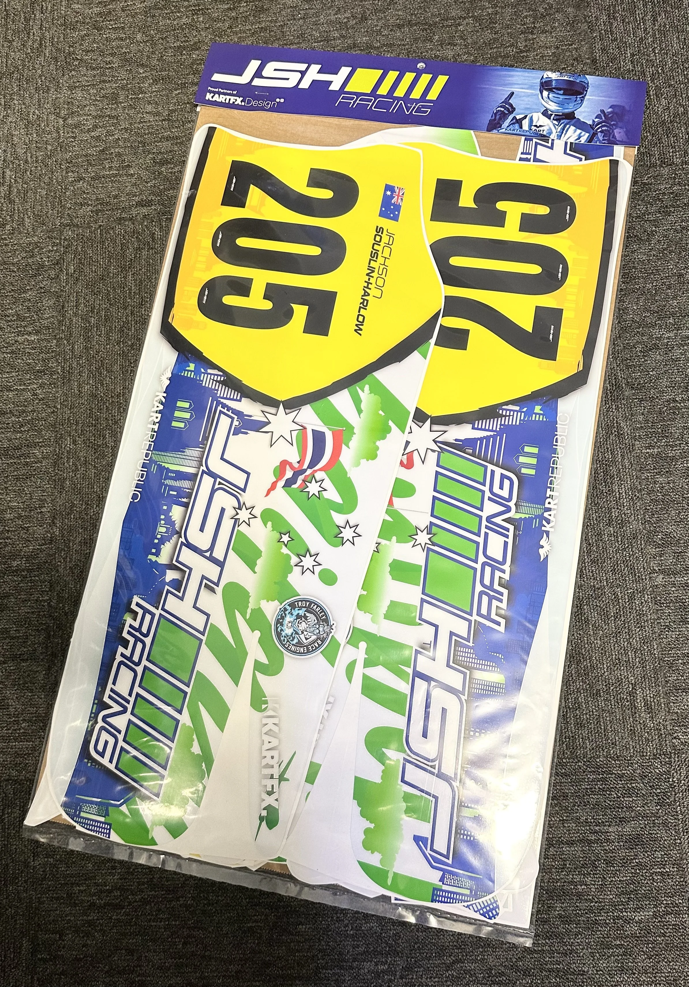 Collection of kart racing stickers and decals, including yellow and black numbered badges, with a KartFX Racing banner at the top.