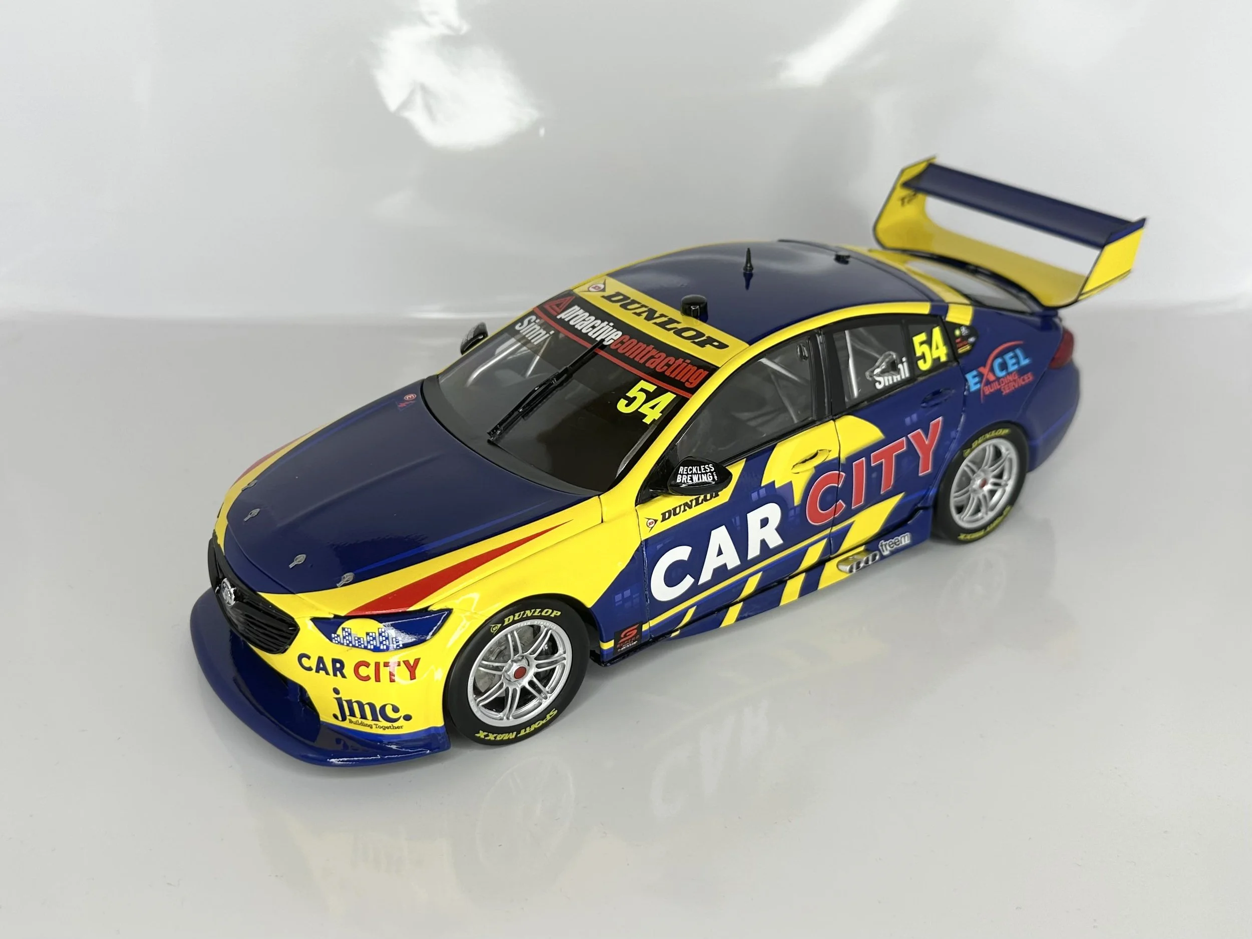 Scale model of a race car with blue, yellow, and red livery, featuring the words 'Car City' and the number 54.