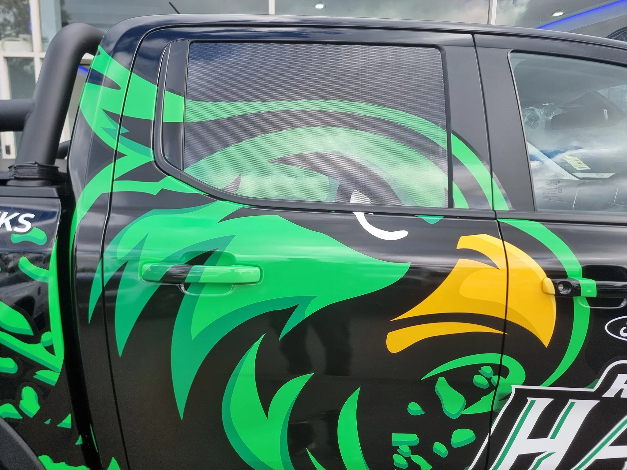 Close-up of a black vehicle with green, yellow, and gray graphic art of a stylized eagle on the door.