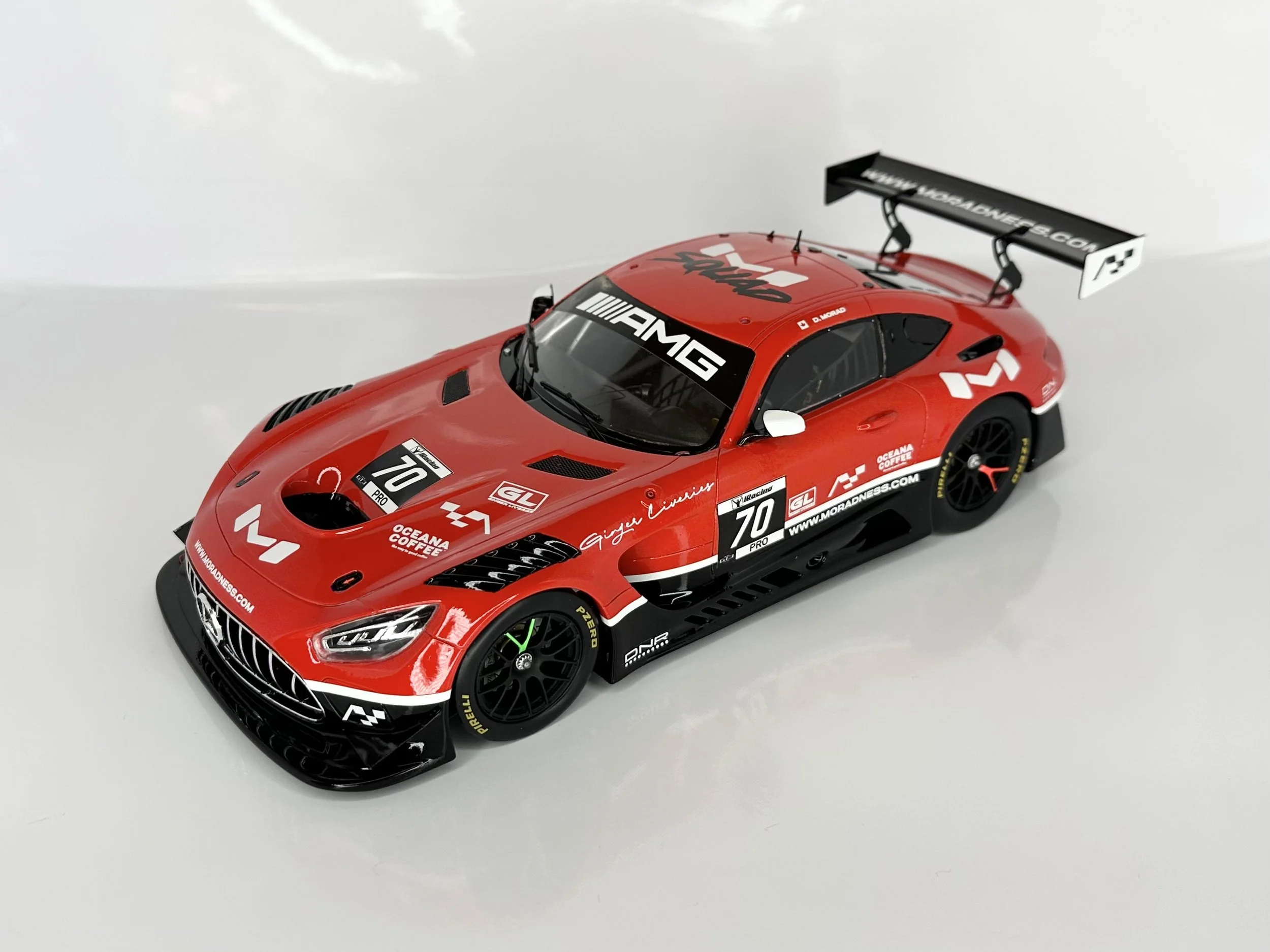 Red race car with black accents and sponsor logos, featuring a large rear wing, racing number 70, and AMG branding.