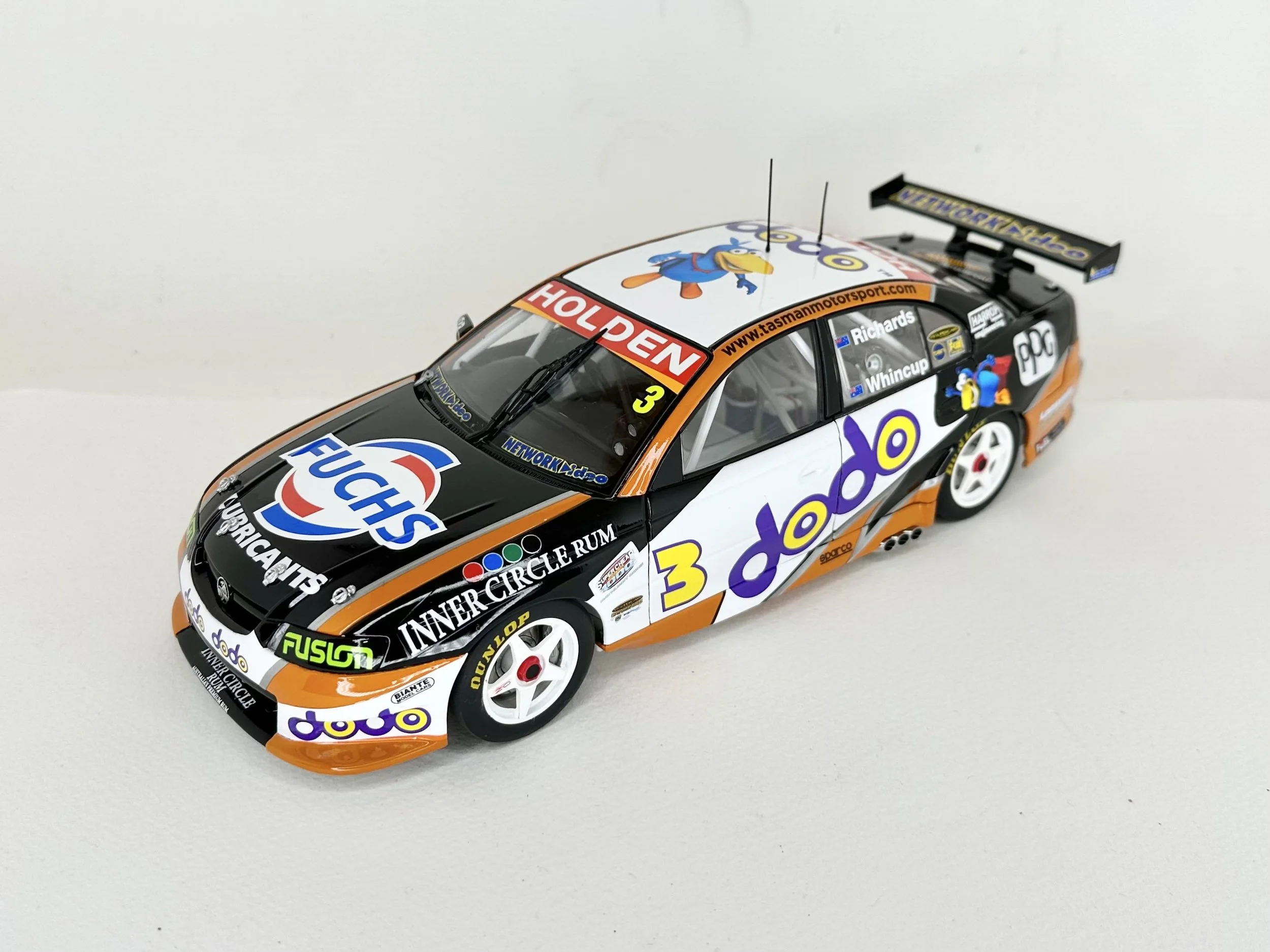 Model race car with sponsor logos, decals, and a large rear wing, featuring a cartoon character on the roof and side.