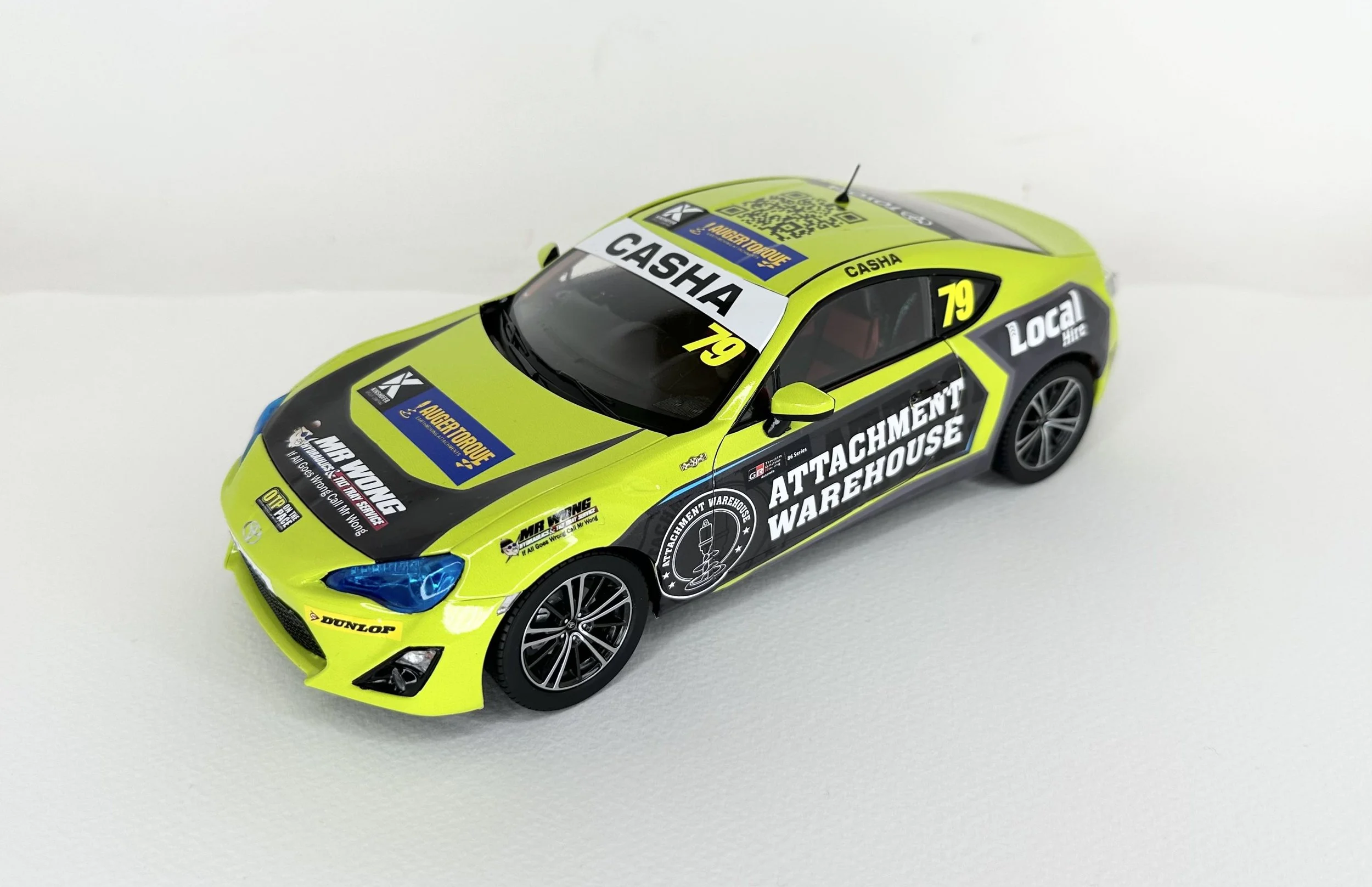 A bright yellow and black scale model race car with sponsorship decals and the number 79, viewed from above and to the side on a white background.
