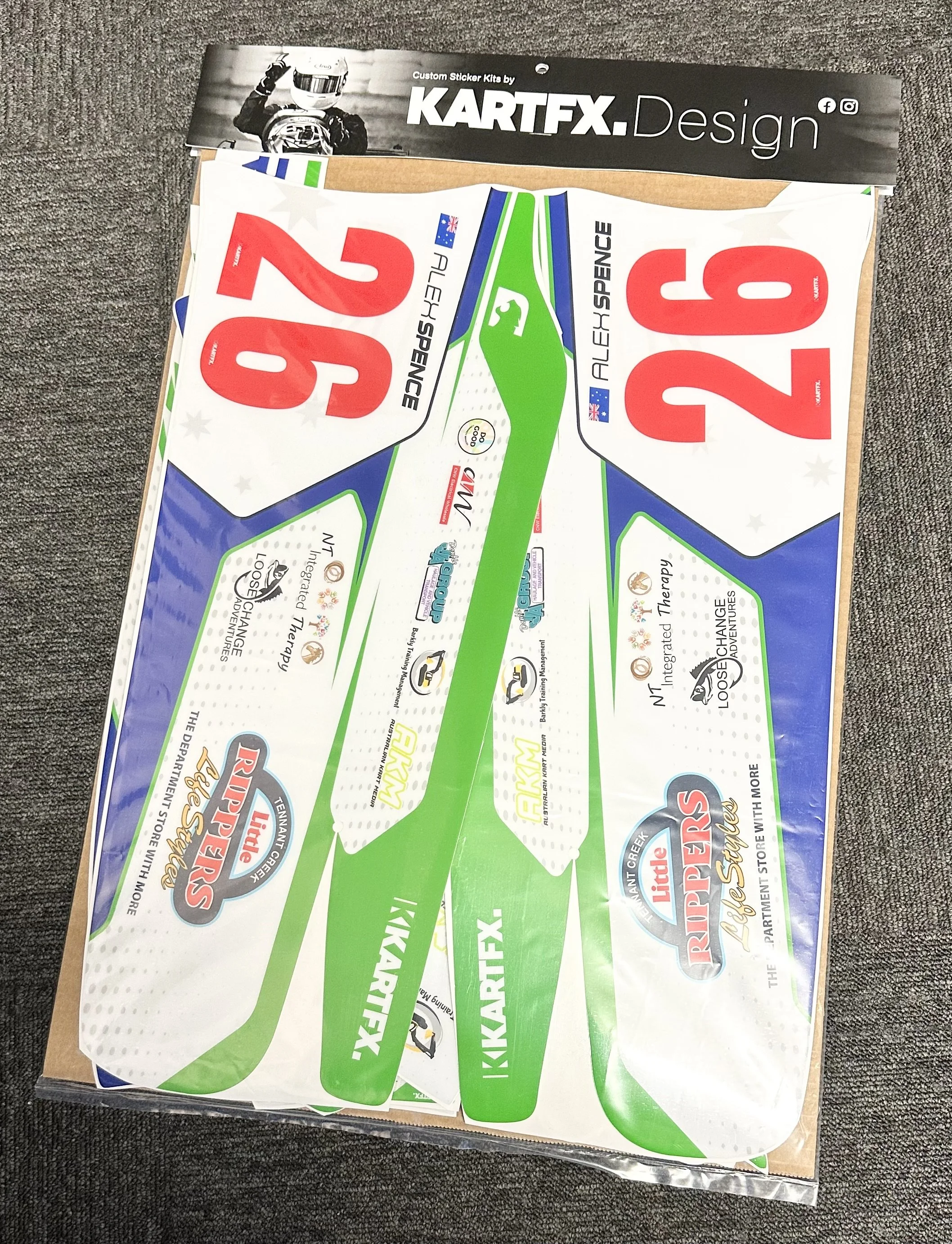 Colorful racing car decals with the number 26 and sponsorship logos, laid out on cardboard.