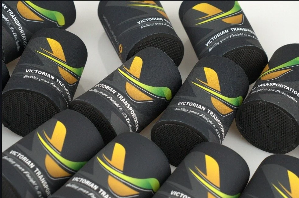 Several black cylindrical containers with a logo of a yellow and green stylized travel bus, and the text 'Victorian Transport' and slogan 'Getting your Freight to its Destination'.