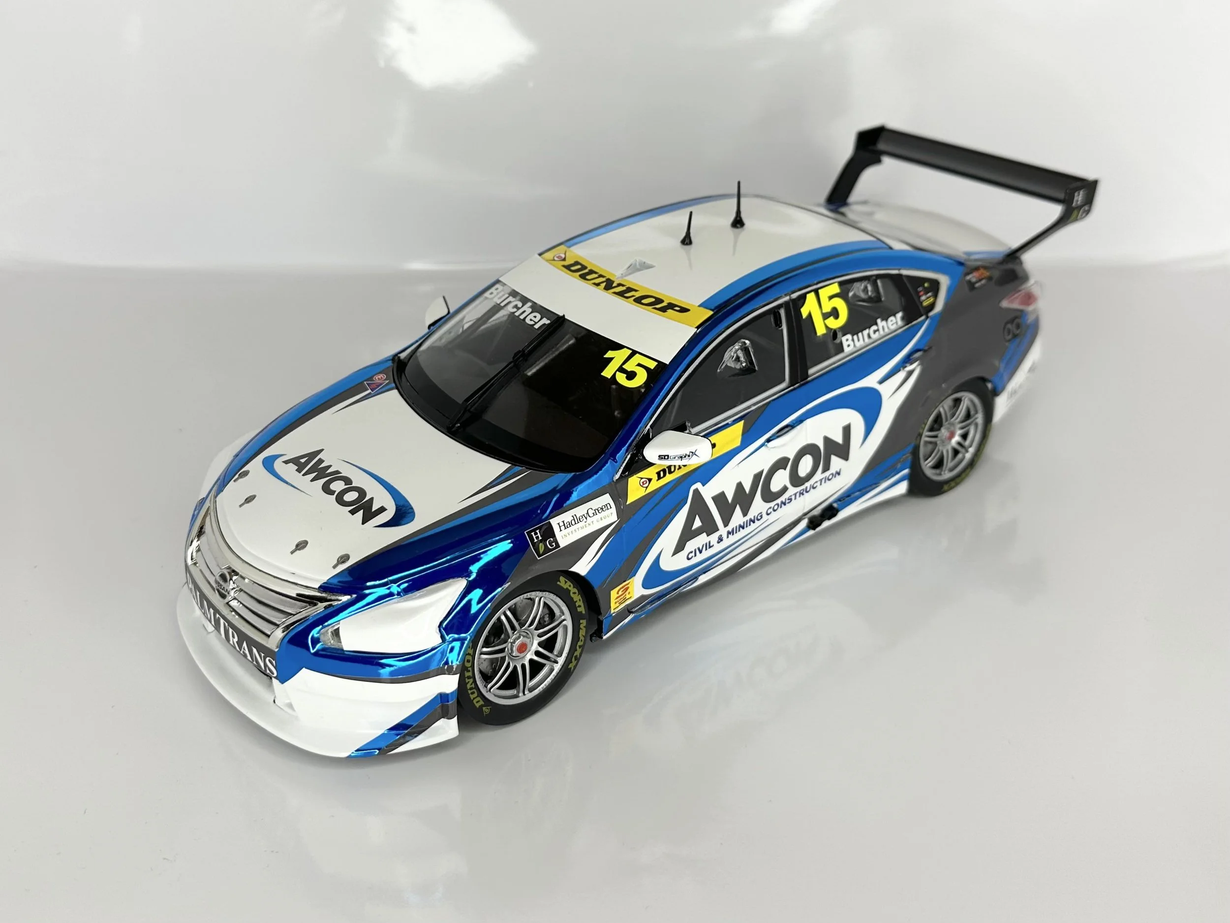 Scale model of a race car with blue, white, and black livery, featuring sponsor logos and the number 15, placed on a white surface.