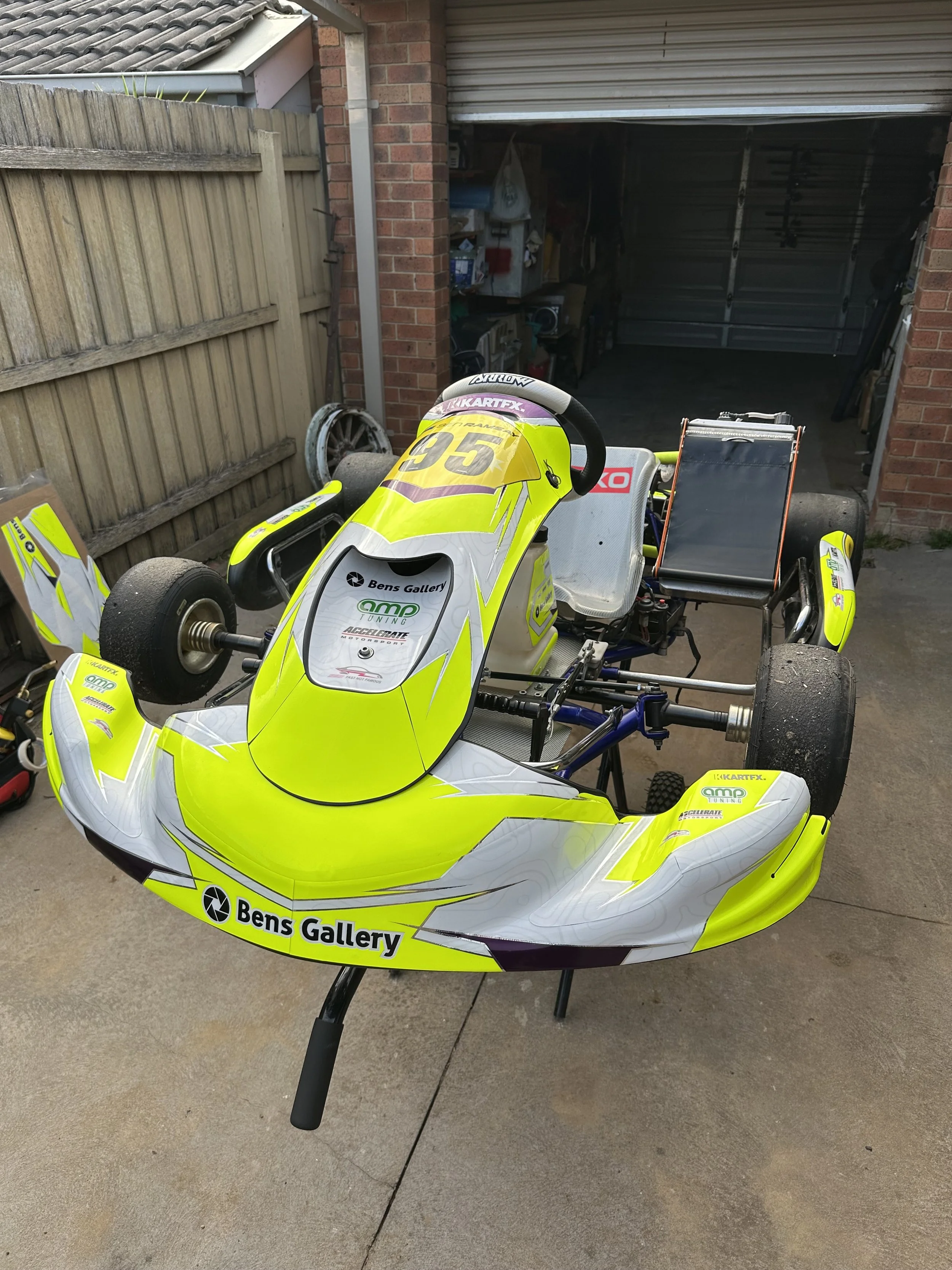 Yellow and white go-kart racing vehicle parked on a driveway.