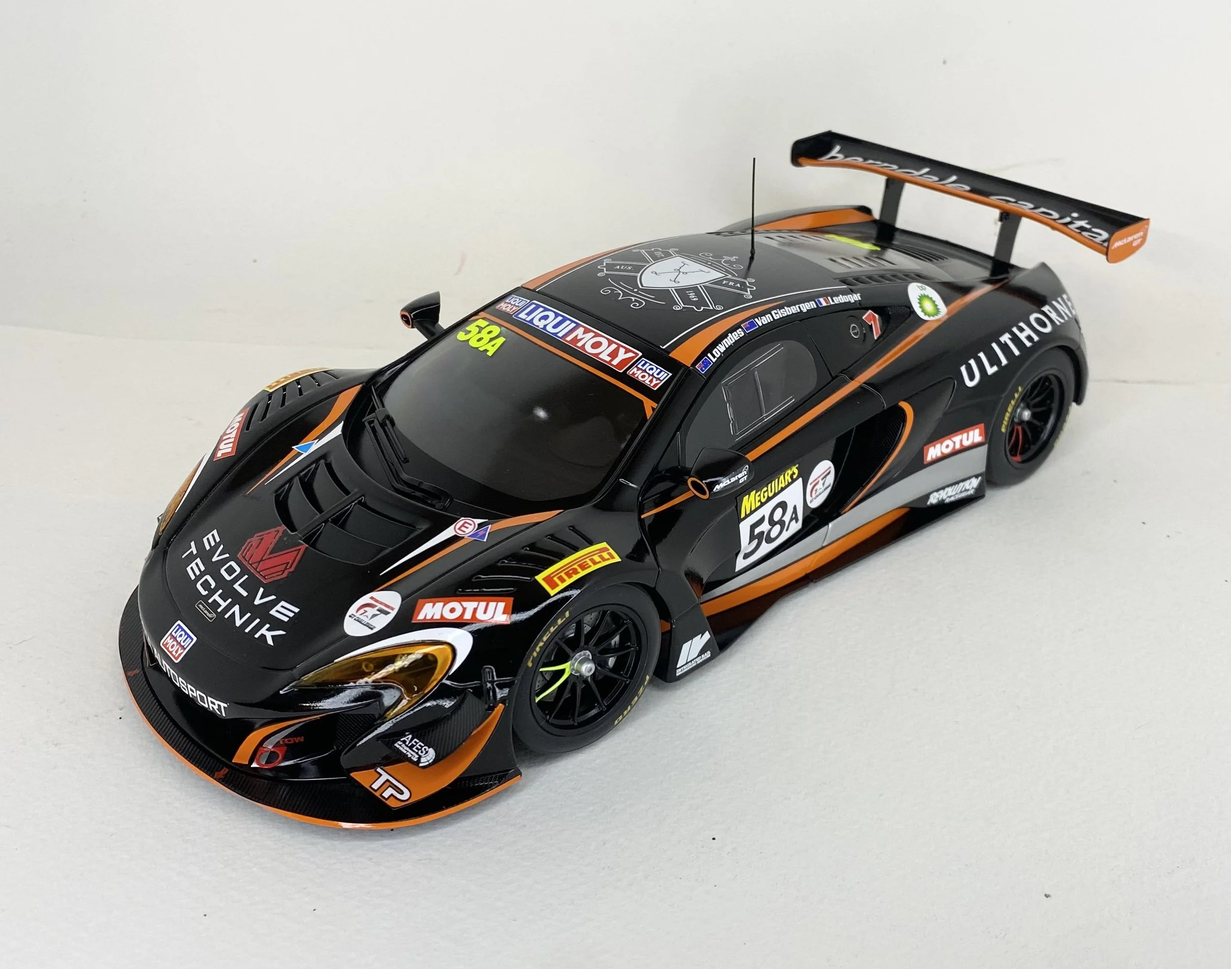 Black and orange race car model with sponsor decals and racing number 58A on a plain white surface.