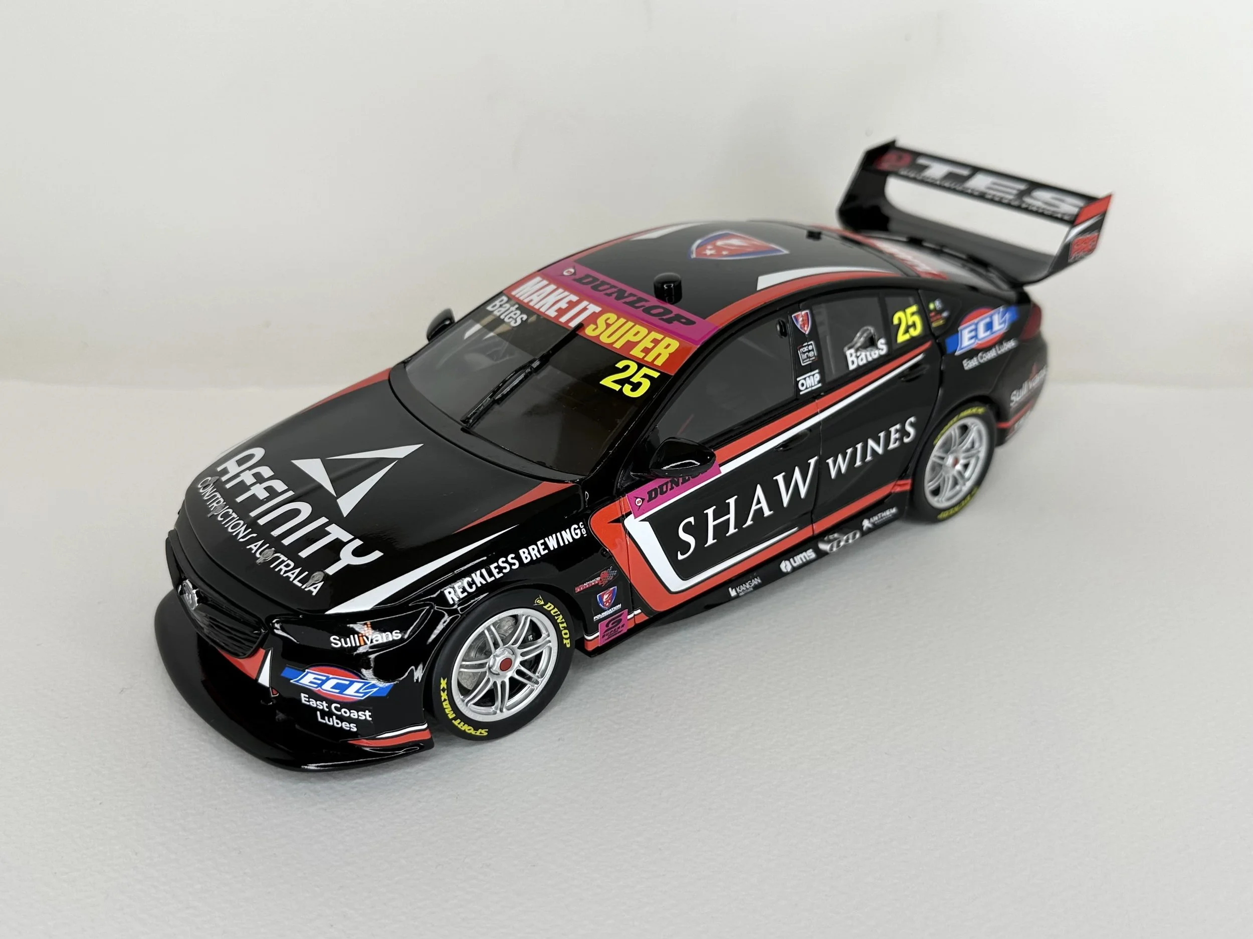 A detailed scale model of a black racing car with sponsor logos, a rear wing, and the number 25, positioned on a white surface.