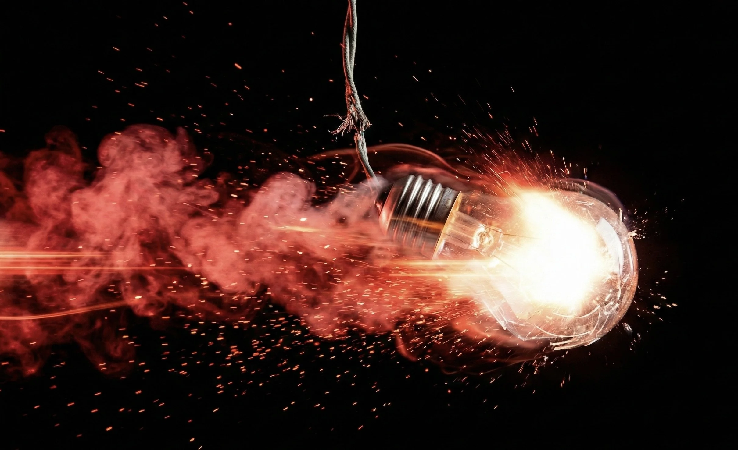 Exploding light bulb with sparks and red smoke on dark background, representing Accendo Marketing's training and mentoring programs that build marketing capability inside recruitment firms