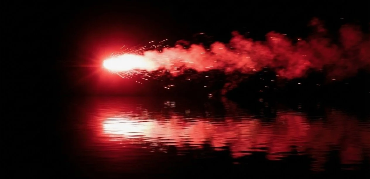 Flare bursting with red sparks and smoke reflected on calm water at night, capturing the moment a recruitment firm connects with Accendo Marketing to ignite its marketing results