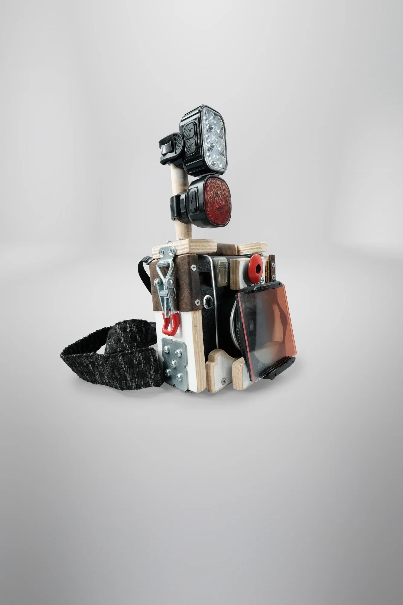 Dual LED bike light flash system mounted on wooden rods—clear white light (top) and red light (bottom). Where white LED lets subjects pretend strange camera might capture 'reality,' red light makes performance pretence impossible. ND filter visible o