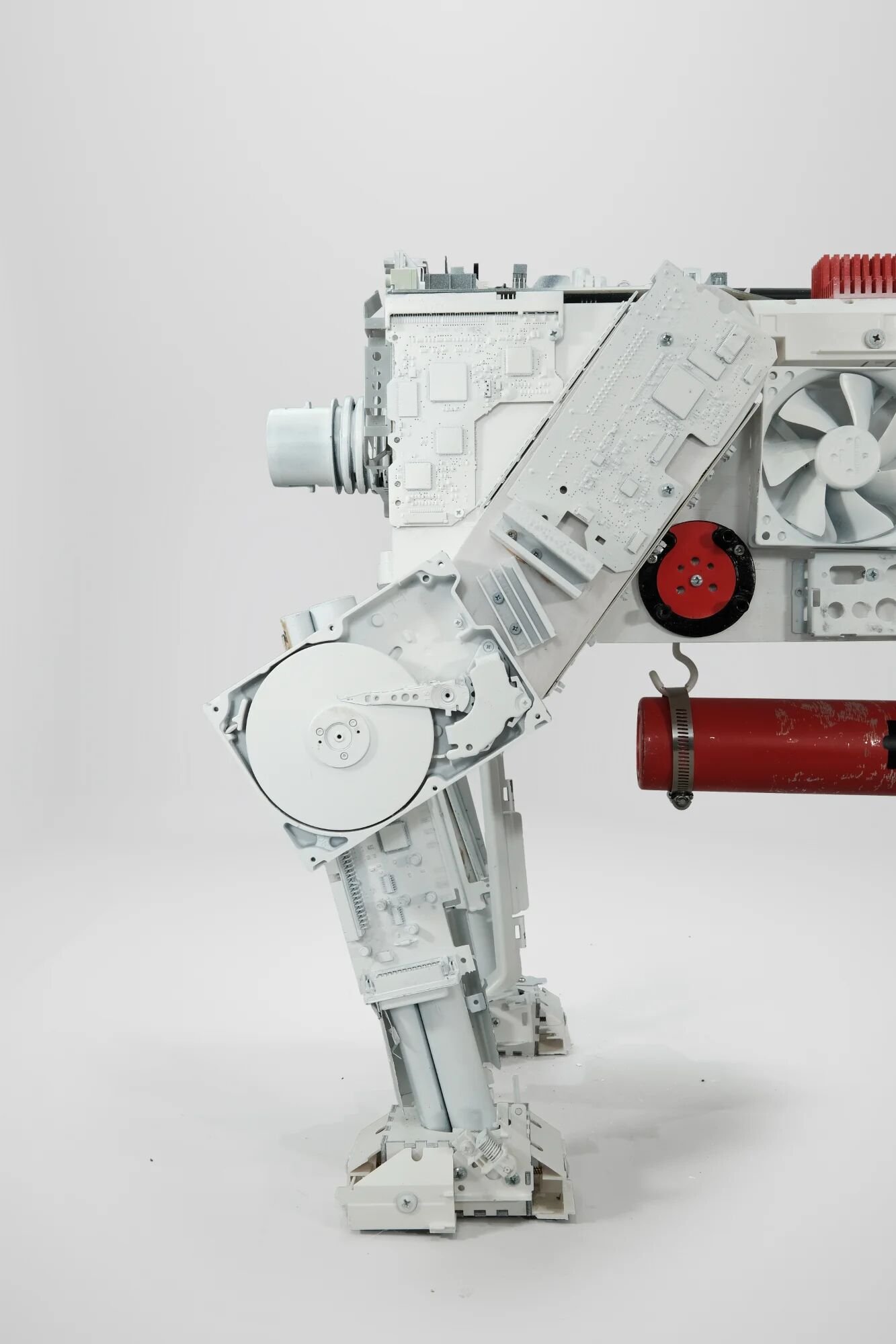 Side profile showing technological corpses beneath mythological skin. Hard drives drilled and screwed into wooden frame, motherboards layered as external skin. Wooden legs with steel rod feet. Hybrid skeleton—not animal, not machine, caught between s