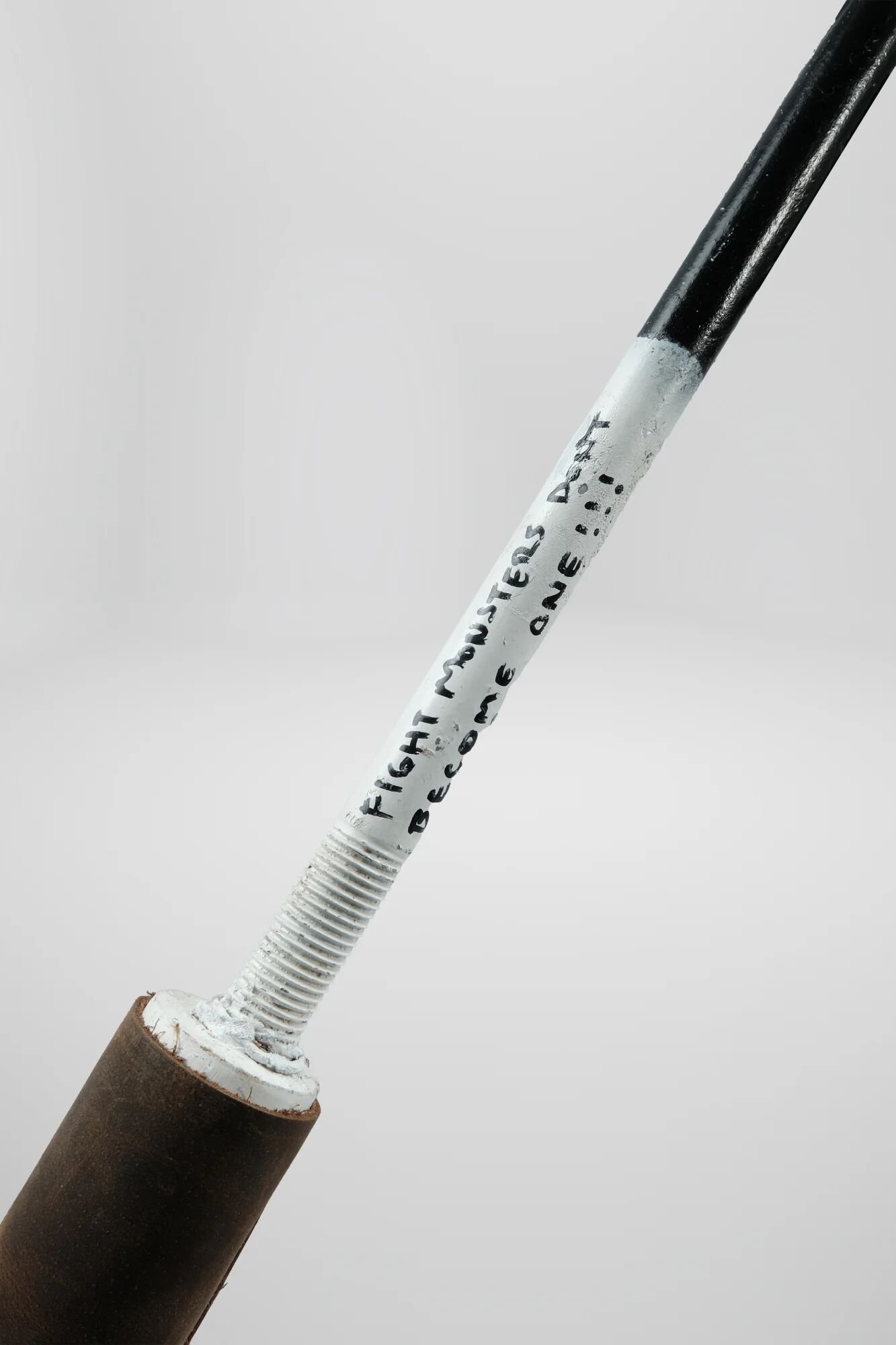 Inscription placed exactly where hand contacts during grip: 'FIGHT MONSTERS BECOME ONE'—Nietzsche's warning encountered through use, not observation. Fought anxiety with cannabis for 24 years. Tool became master. Medicine became addiction. Became the