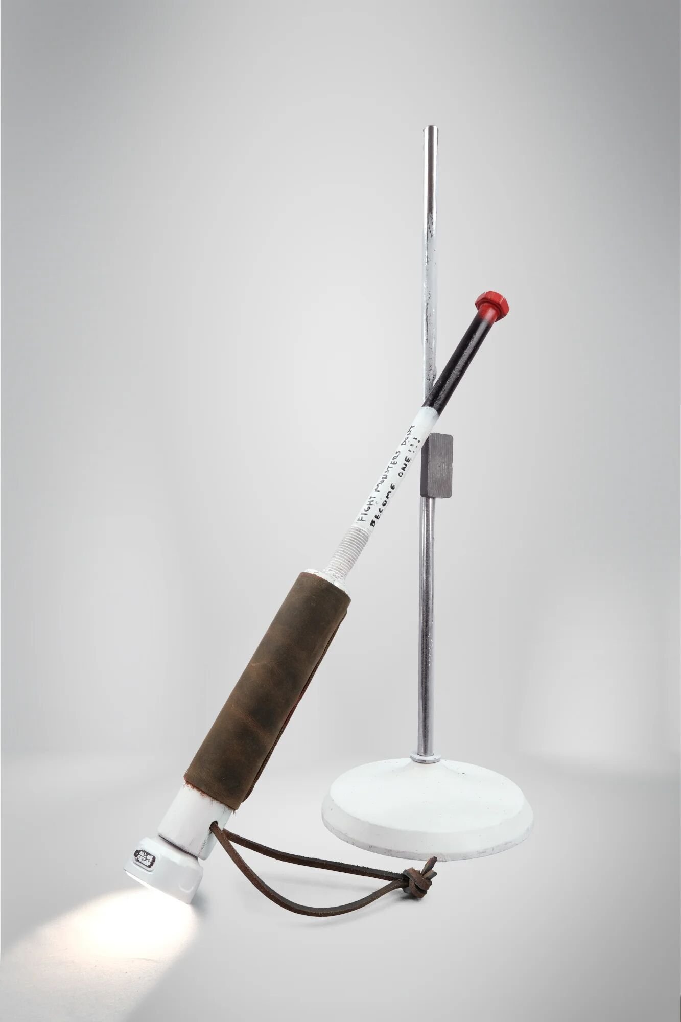 LED bike light activated—navigation mode whilst violence trails behind unused. White handle, leather grip, red tip visible. Geometric inversion structural: orientation determines which destruction deploys. Capacity persists unchanged.