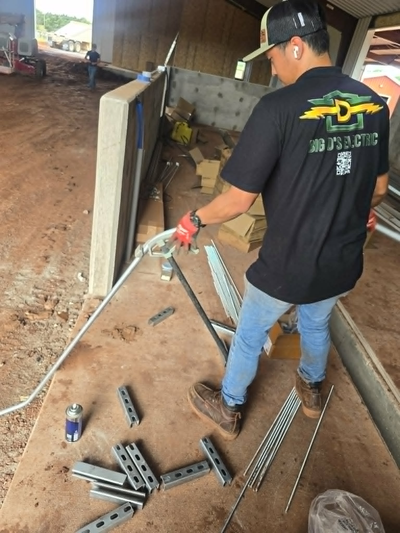 Worker installing conduit and showing Big Ds logo and information on shirt.