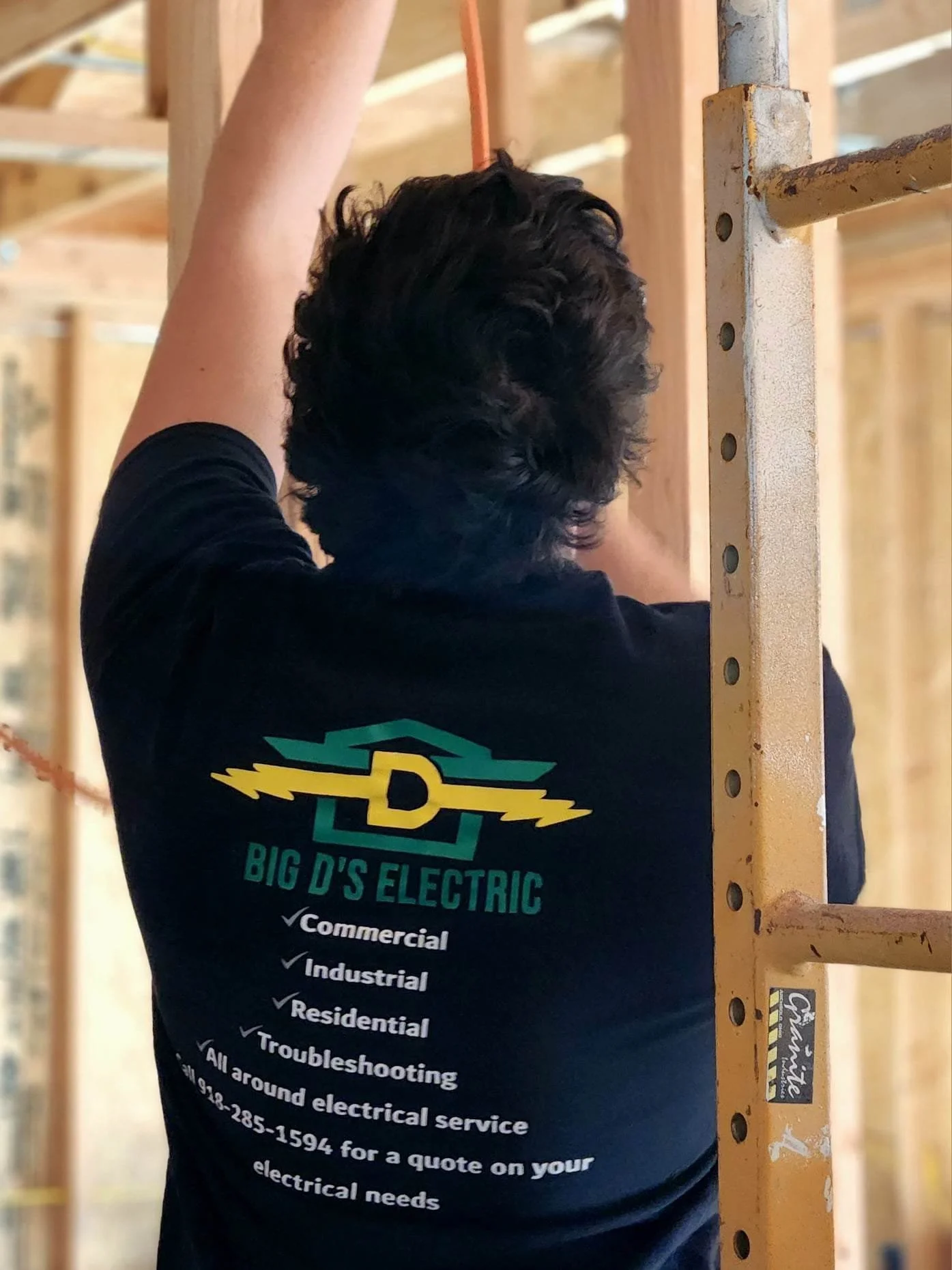 Big Ds working from behind wearing shirt showing logo and business information