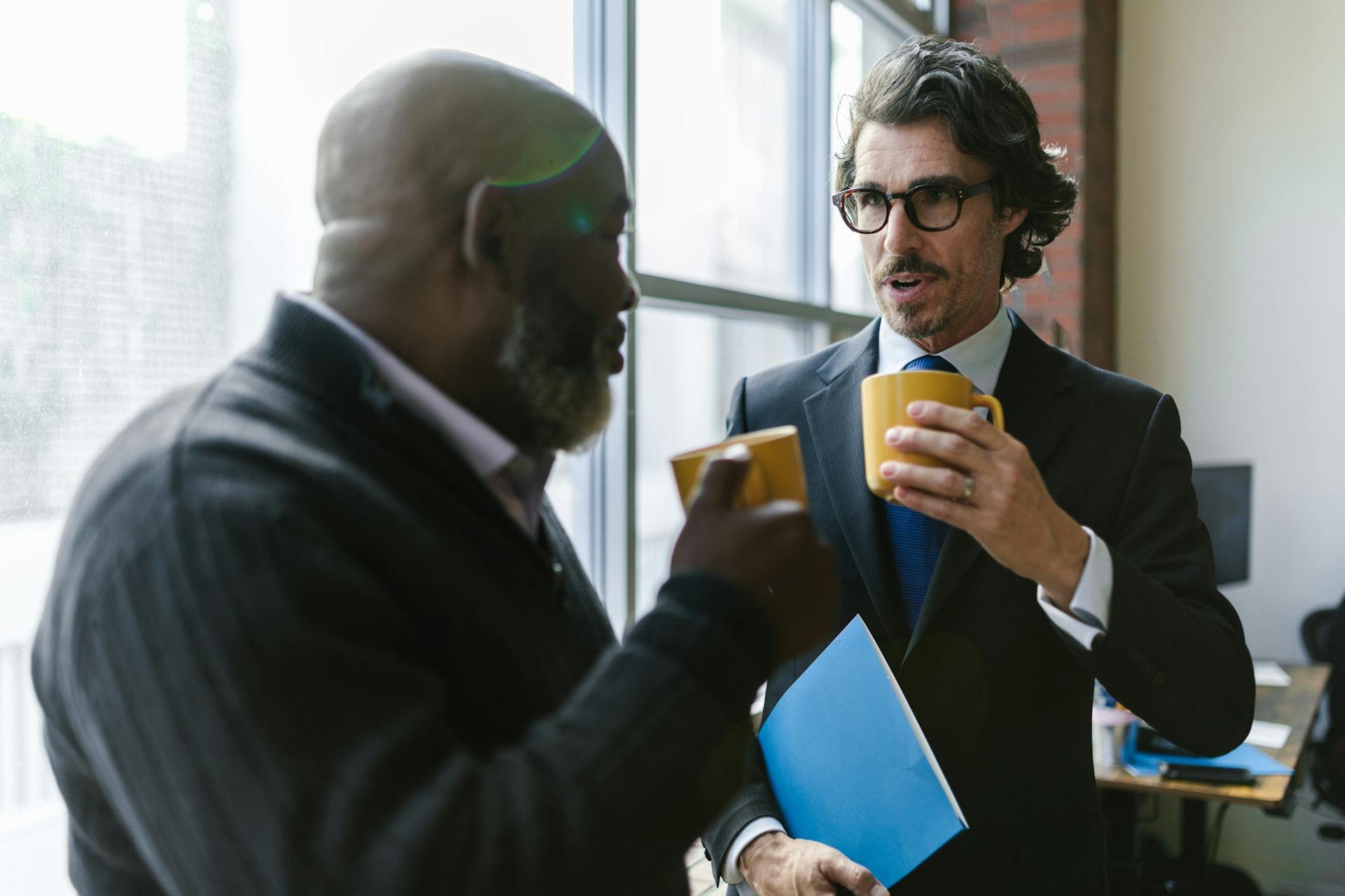 Two men having a discussion in an office after receiving cosmetics for men in Victoria, BC.