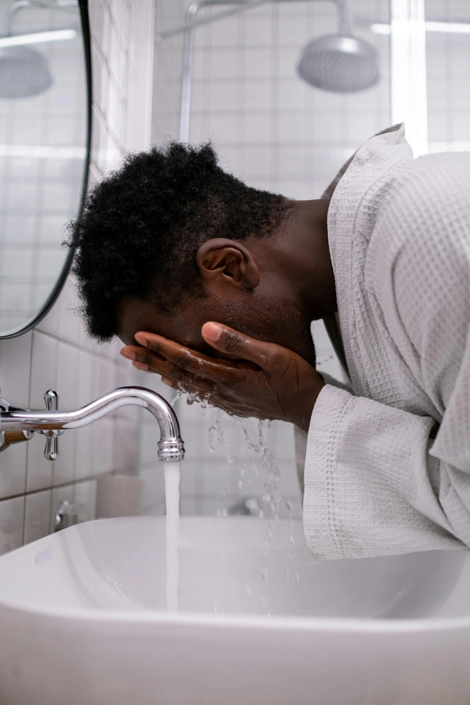 A young man washing his face after receiving cosmetic treatments for men at Victoria Men's Health Clinic.