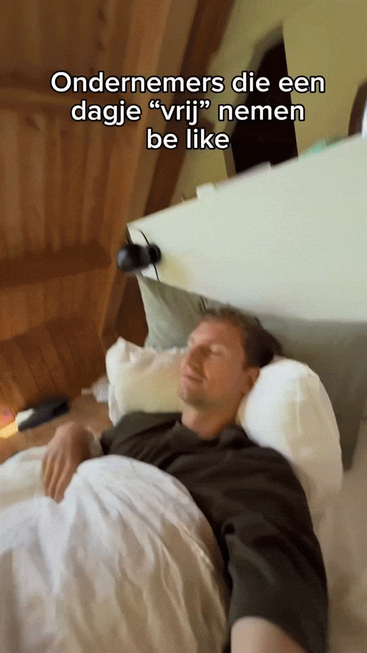 A man sleeping in bed with a pillow, with a caption in Dutch.