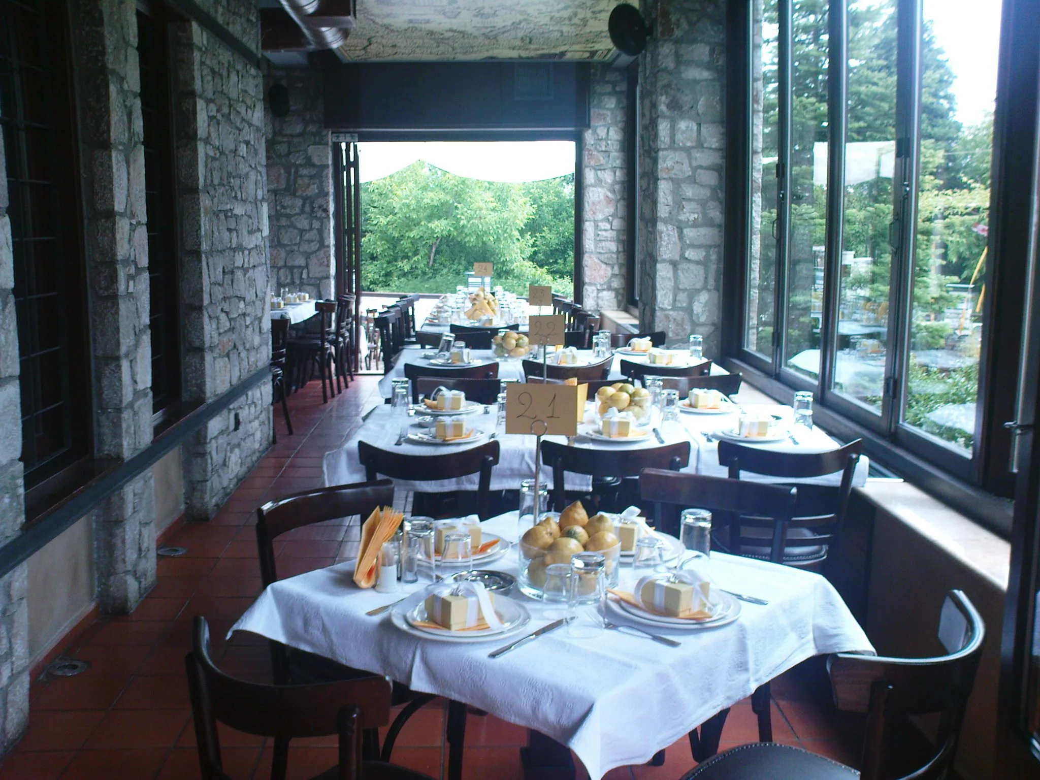 Τραπεζαρία στο Φαγοτόπι έτοιμη για εκδήλωση, με λευκά τραπεζομάντηλα, διακοσμητικά και θέα στο πράσινο της Λίμνης Πλαστήρα.
