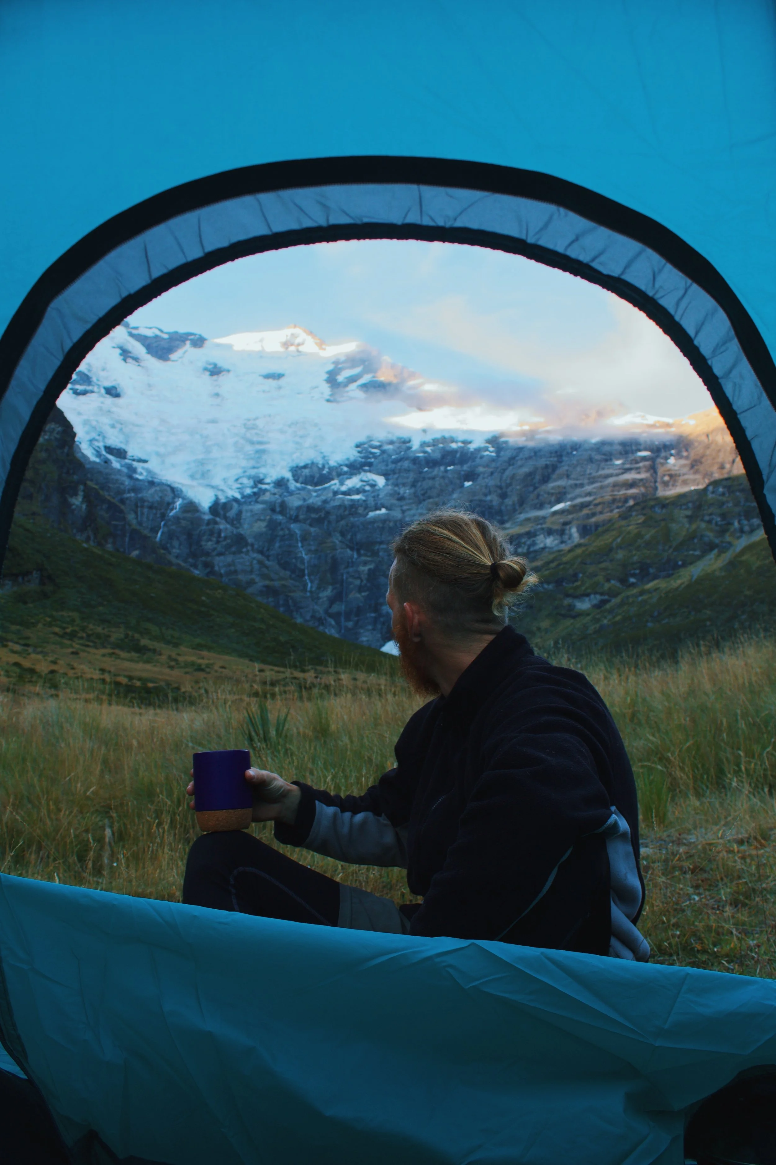Camping in a tent in New Zealand looking at glacier and waterfall