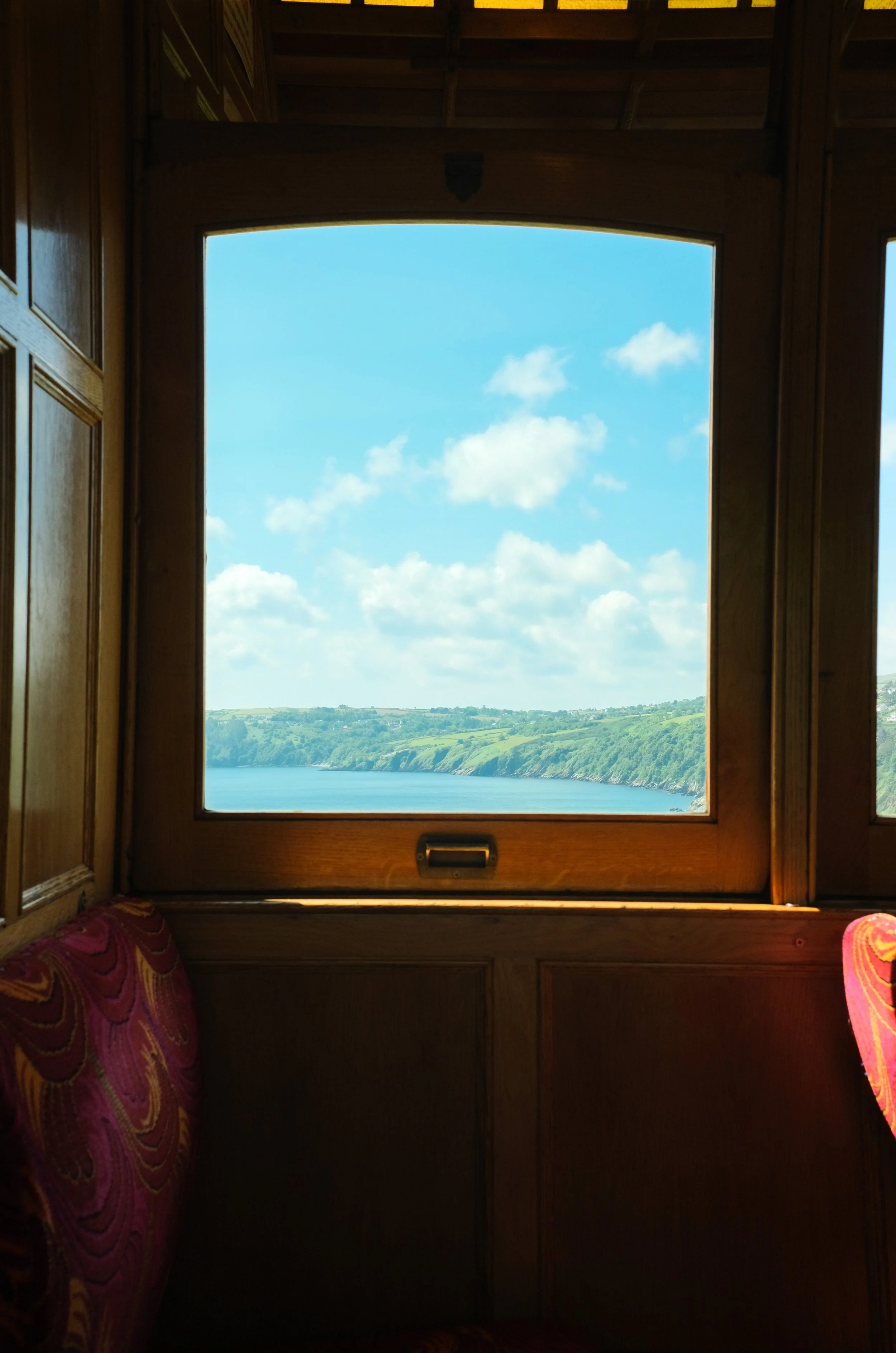 Looking out of a vintage Isle of Man tram carriage window at blue sky and sea