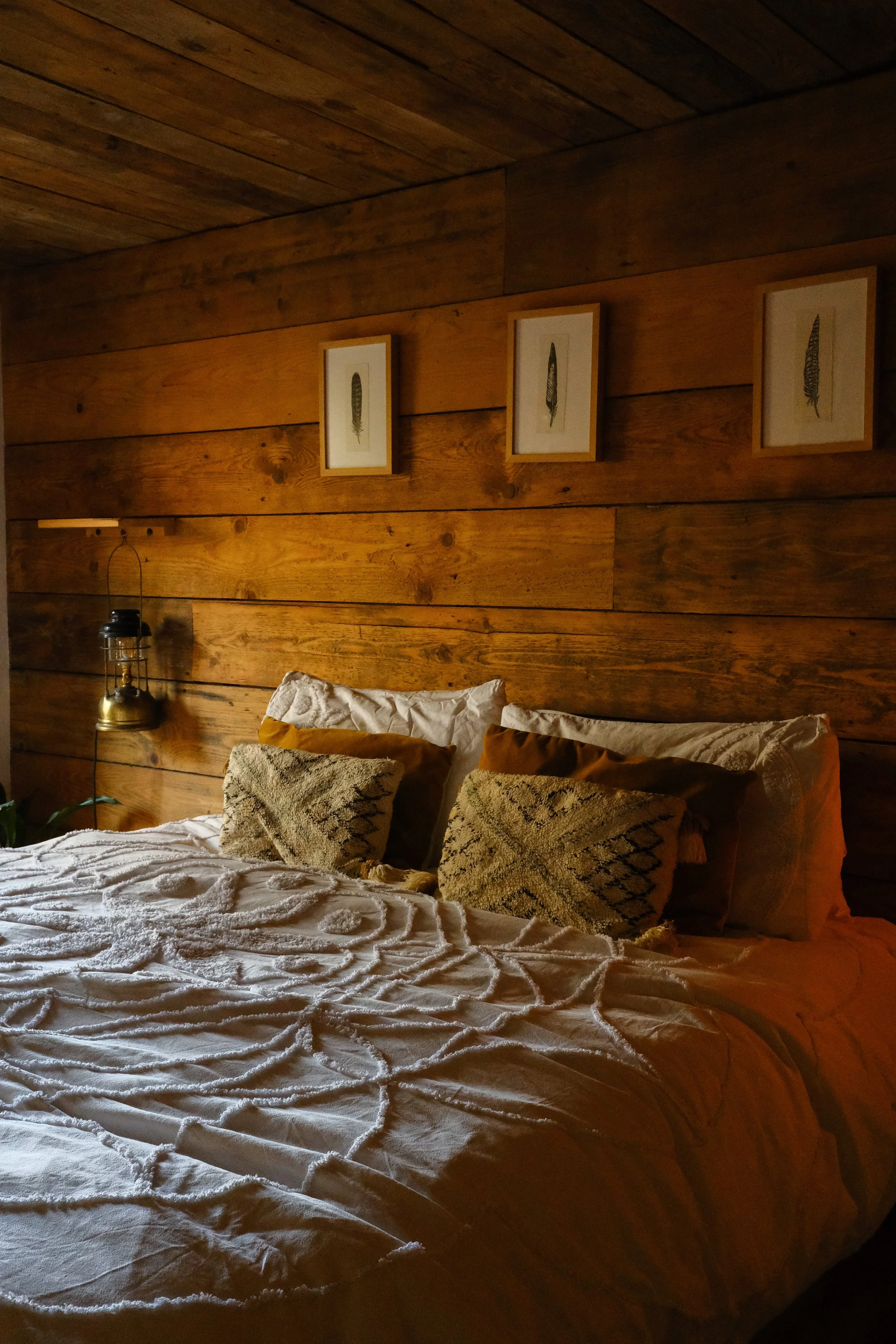 A freshly made bed in a wooden welsh cabin with pillows and lamps