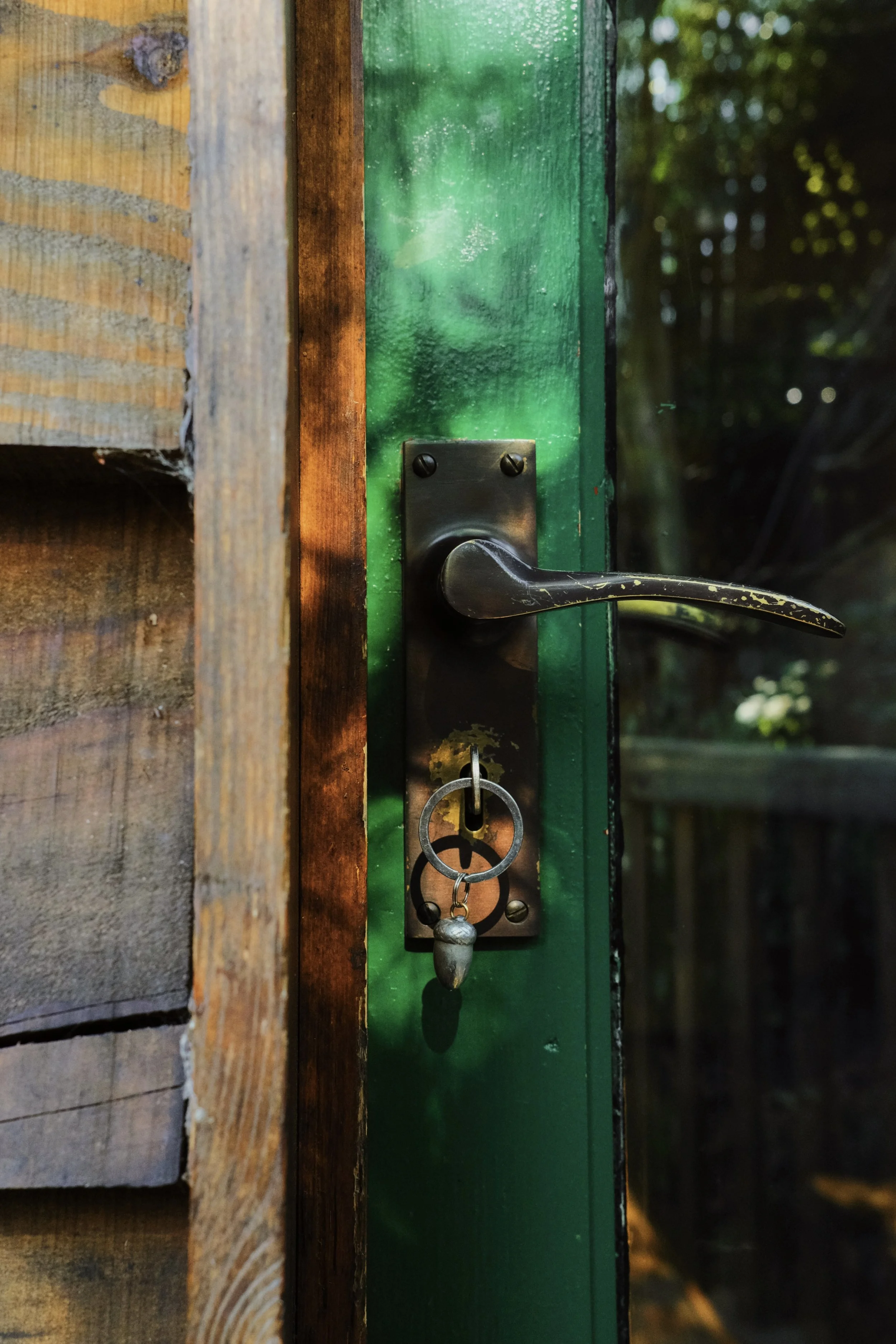 An acorn keyring on a key in a green door of a wooden cabin