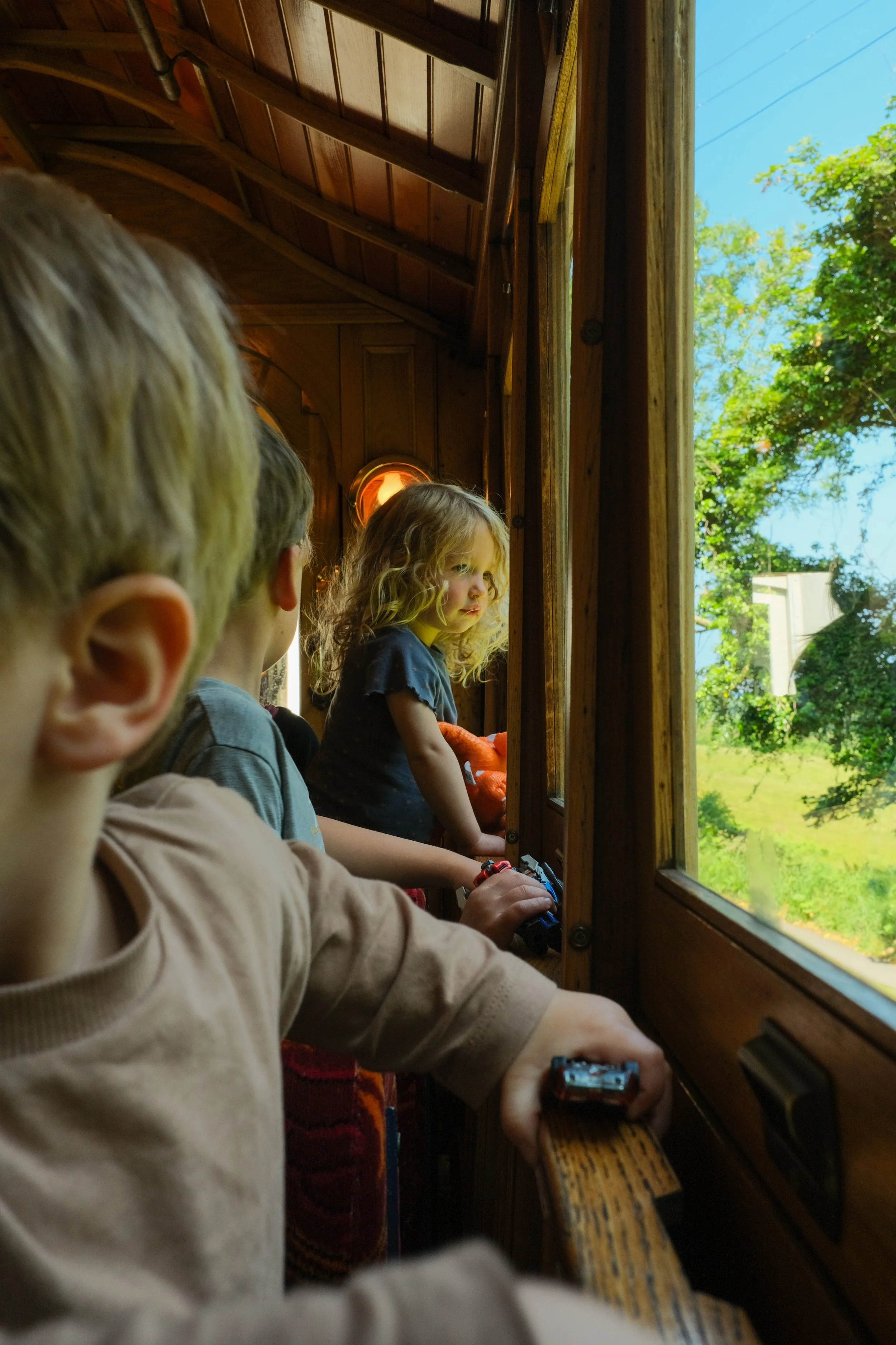 Toddlers looking excited on a tram looking out the window