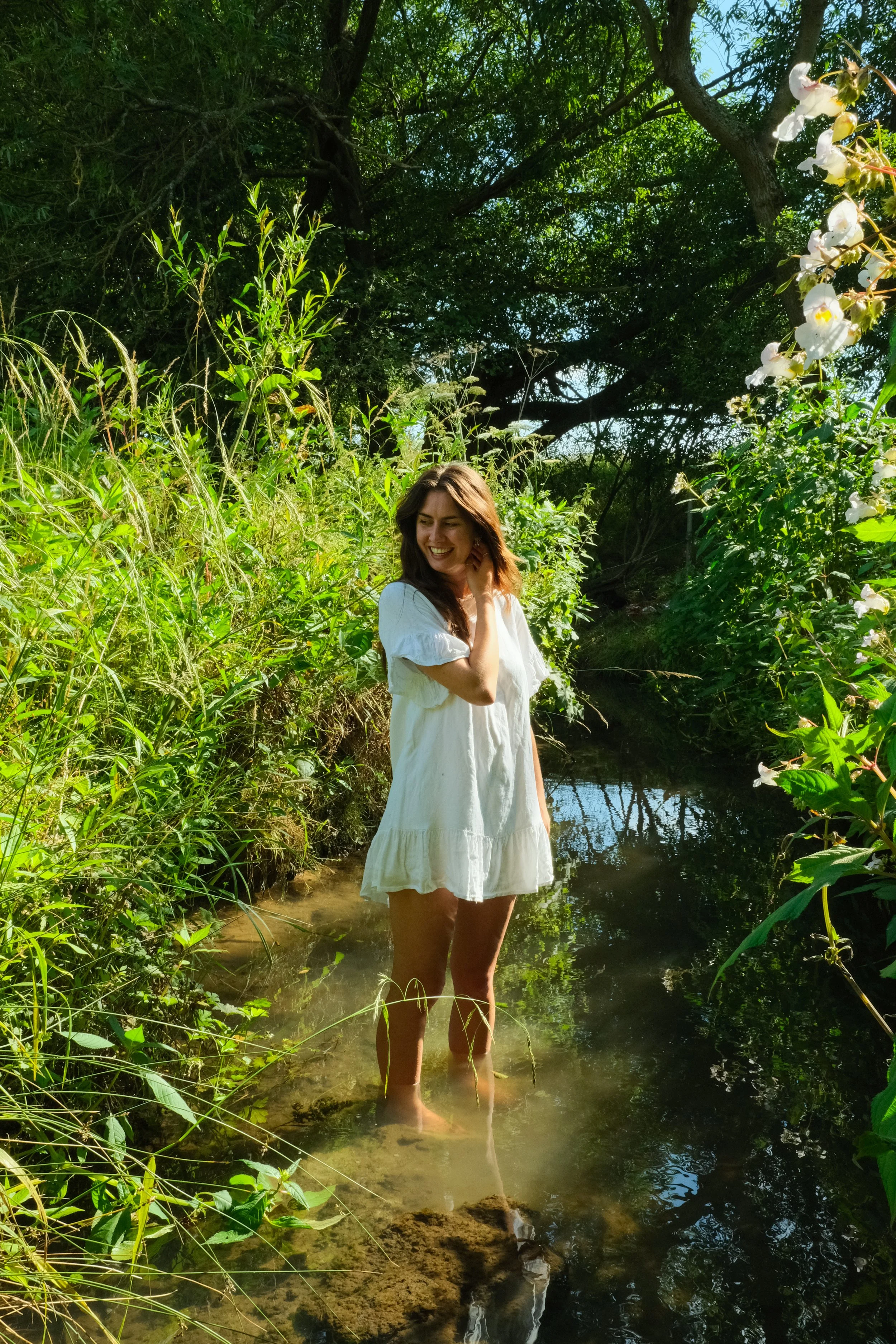 A girl in a summer dress, stood in  stream 