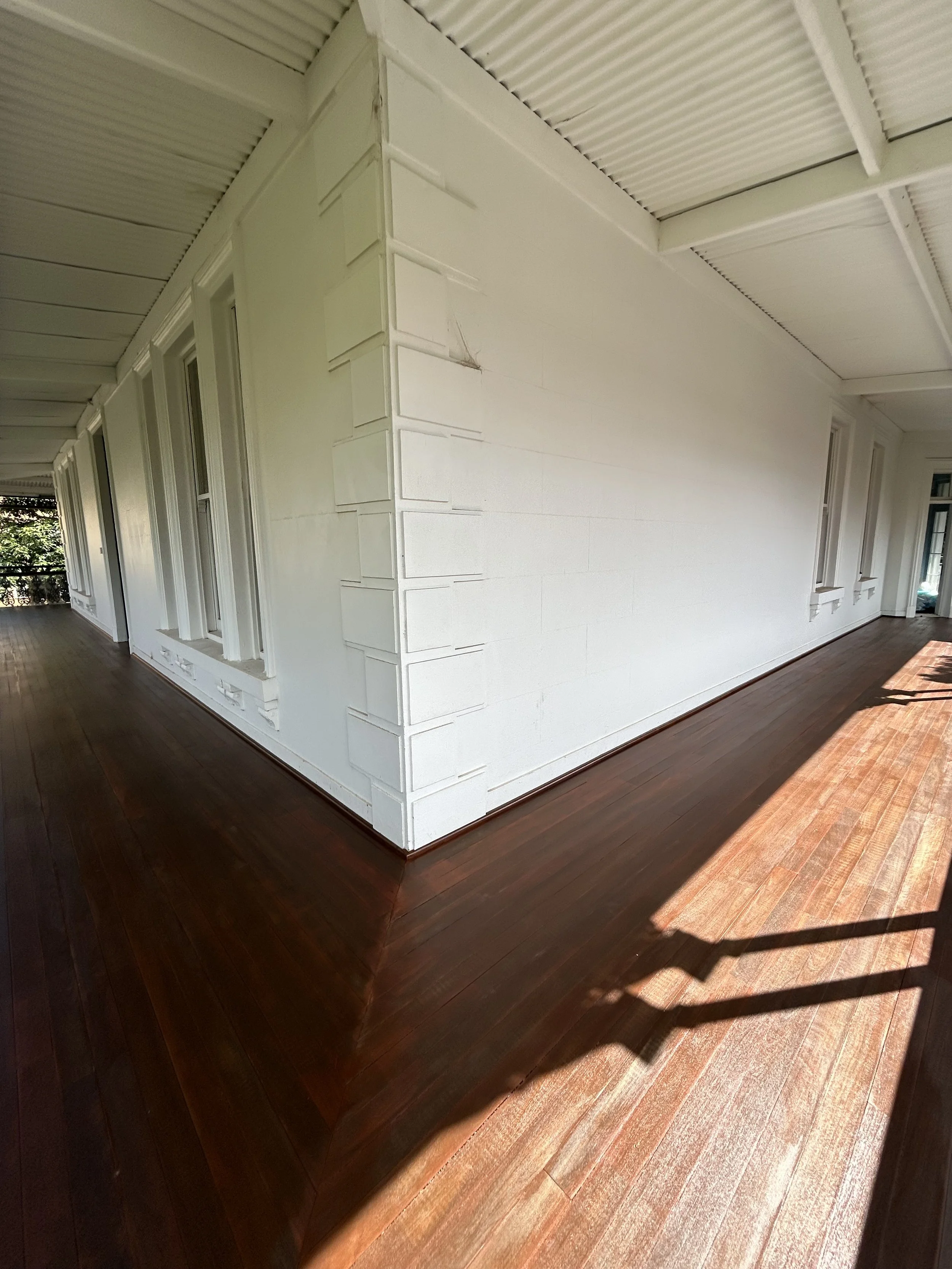 Indoor porch with white walls, large windows, and dark hardwood floor.