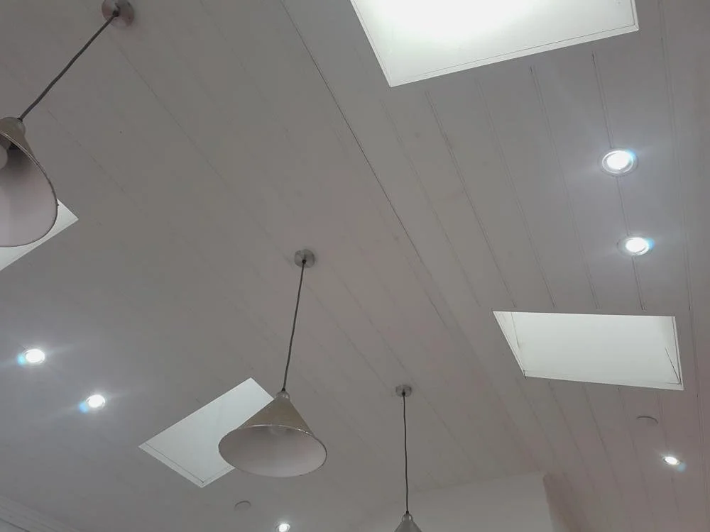 Ceiling with skylights, led lights, pendant lights, and a skylight in an interior space.