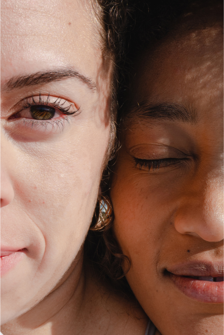 Close-up of two women with their faces touching, one with light skin and the other with darker skin, both with eyes closed and expressing calmness and connection.