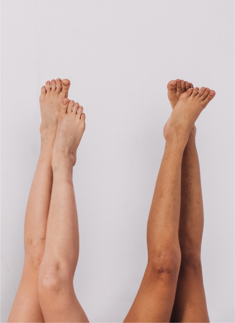 Two pairs of legs raised with feet pointing upward against a plain white background.