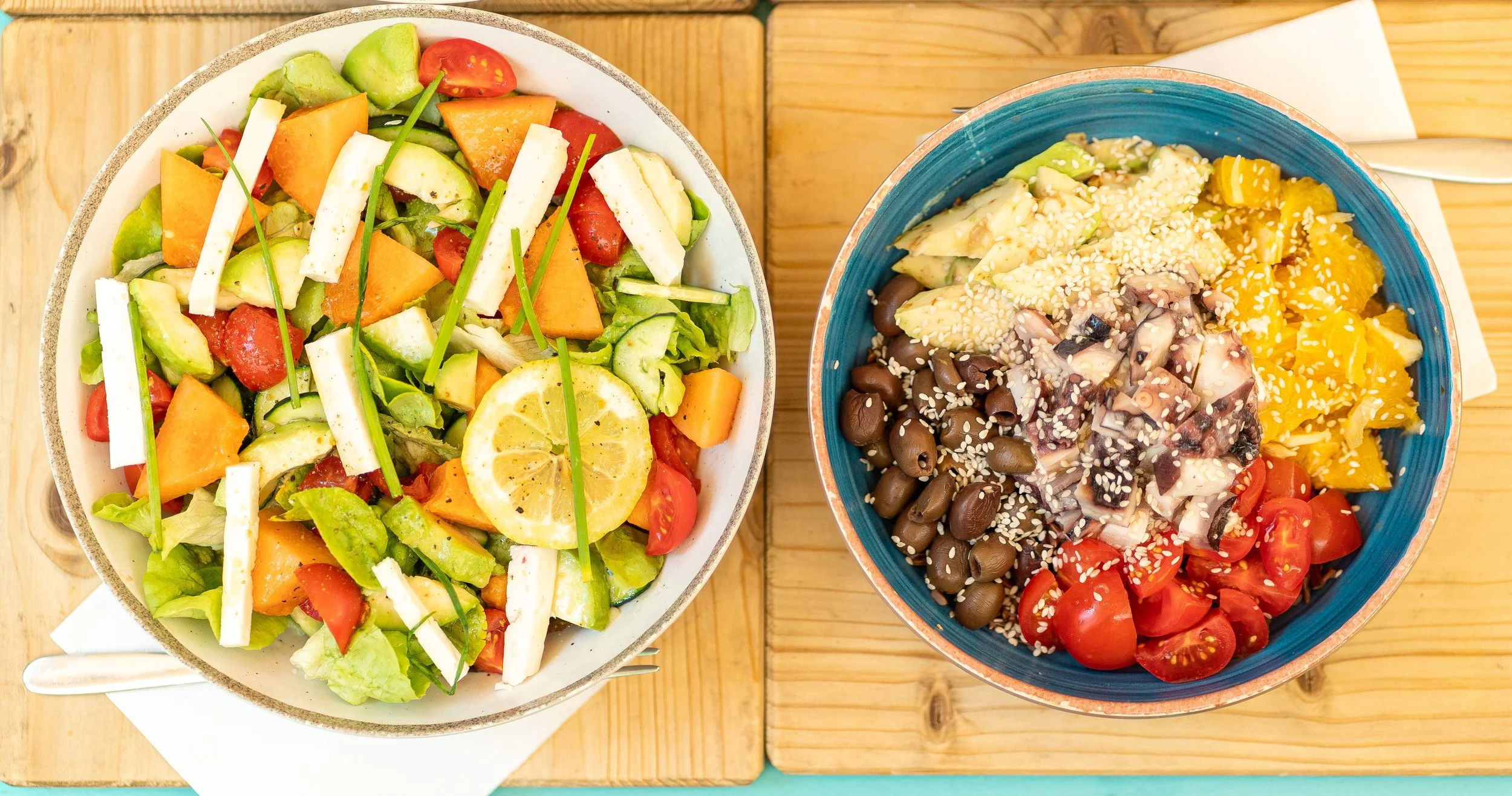 Insalata di verdure fresche con limone, e ciotola di insalata con pomodorini,mais, olive, mozzarella, alghe, semi di sesamo su un tavolo di legno.Pizzeria Alfiero Orto di Alfiero Marina di Massa.