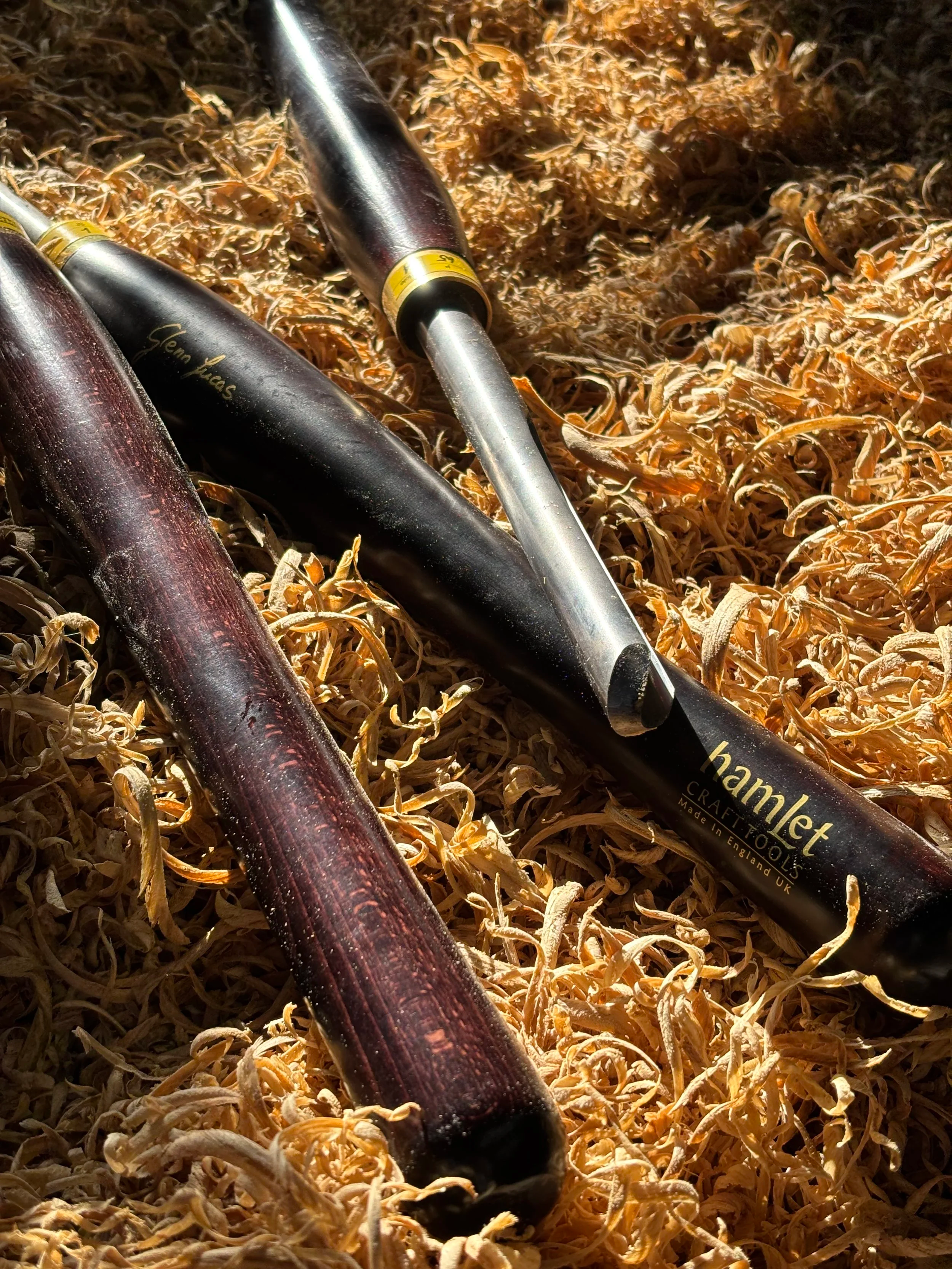 tredreiejern liggende på en seng av flisene i tre, med en av verktøyene som er utstyrt med en kort metallstang og et skjærehode.