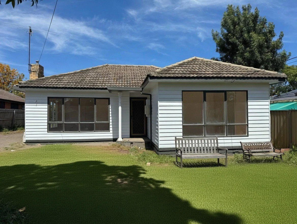 A white house with a tiled roof, large screened windows, a front door, and two benches in the front yard. There is a tree and a blue sky with some clouds.