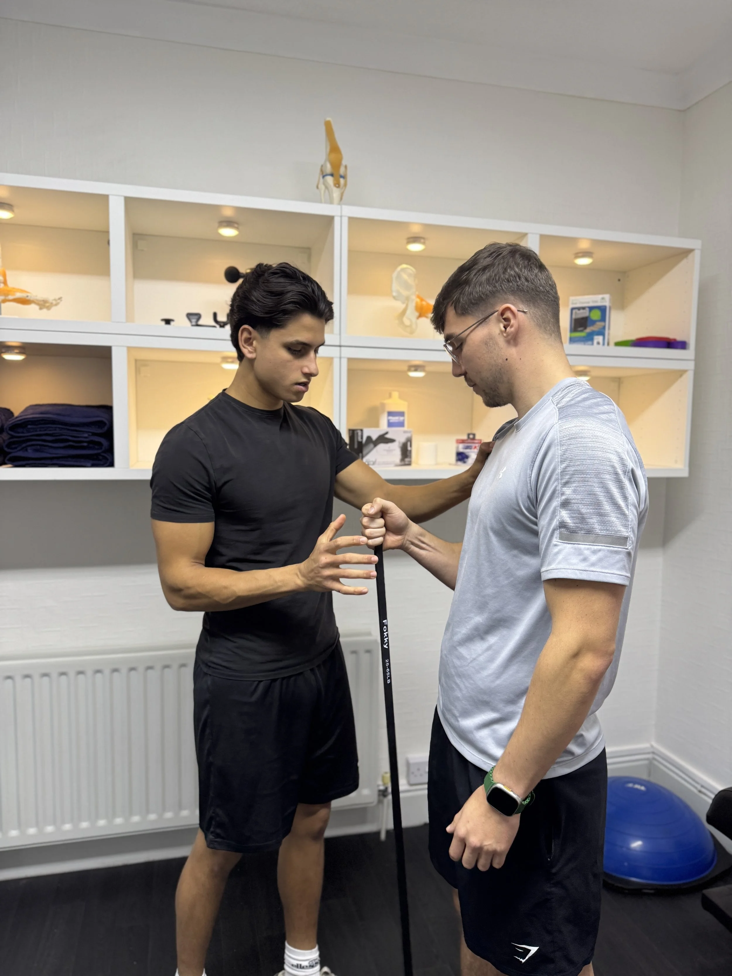 A sports therapist guiding a patient performing a rehabilitation exercise.
