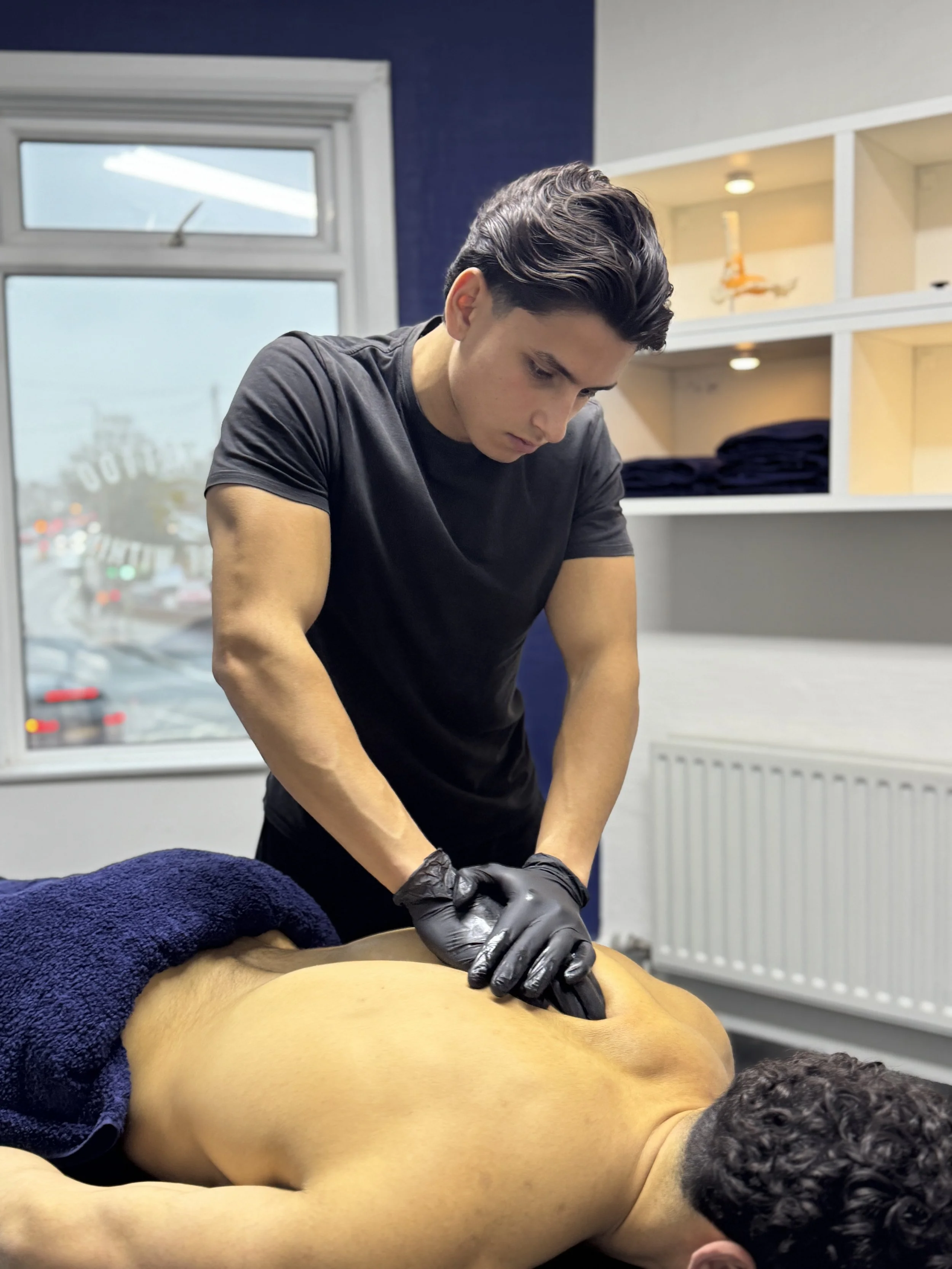 A person giving a back massage with oil on their back.