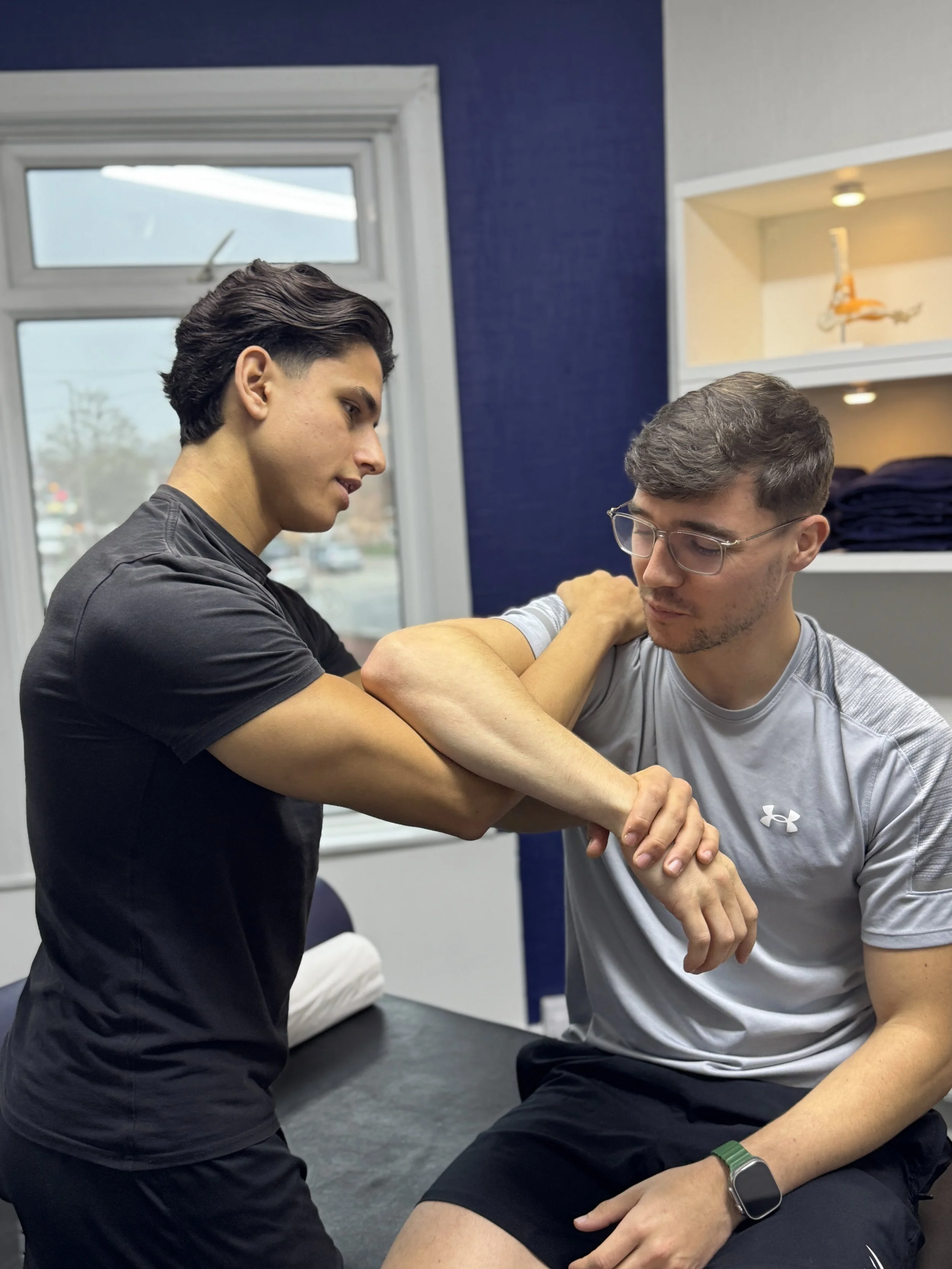 A sports therapist assessing a patients shoulder injury
