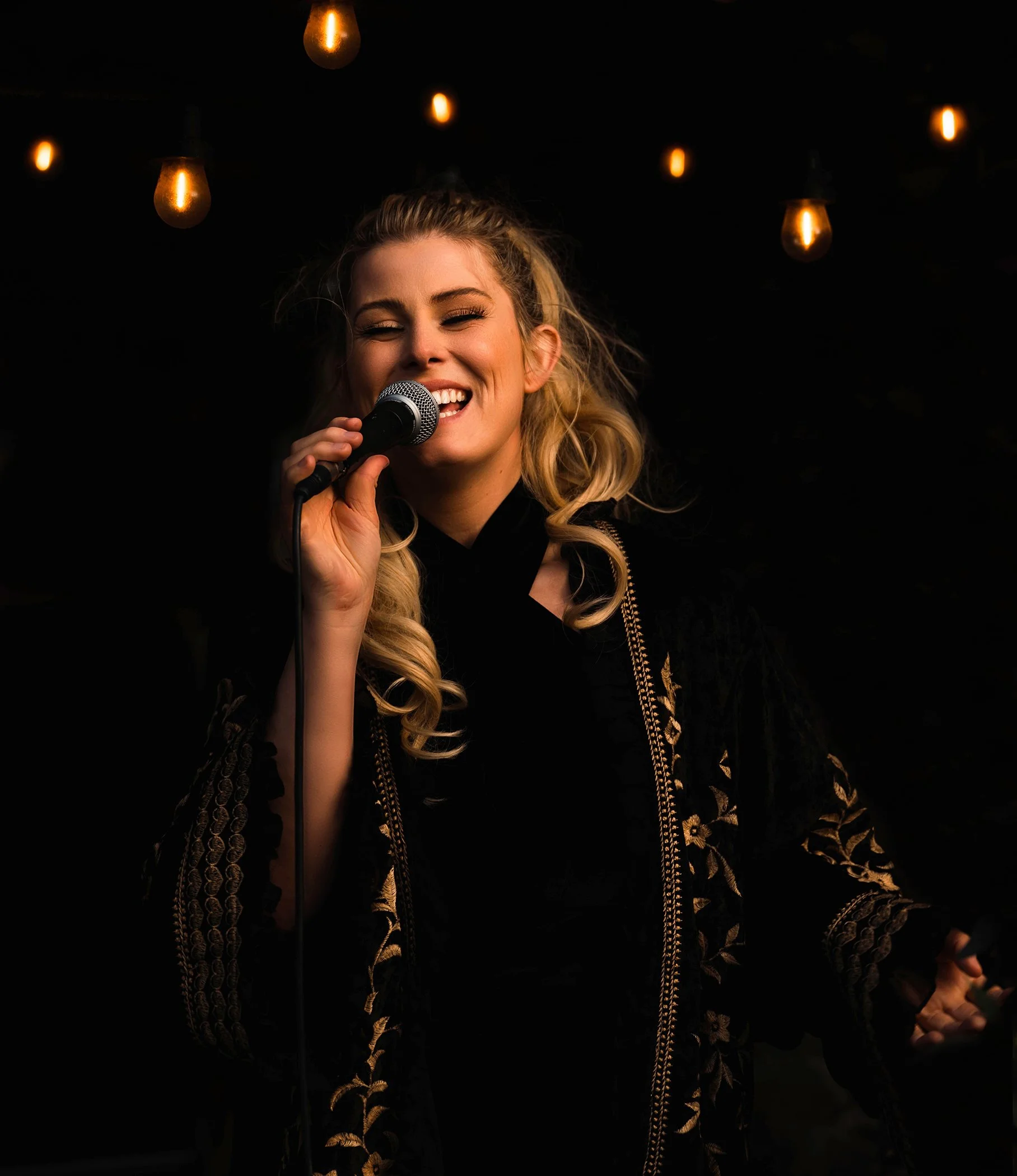 Singer performing at an evening event under warm lighting