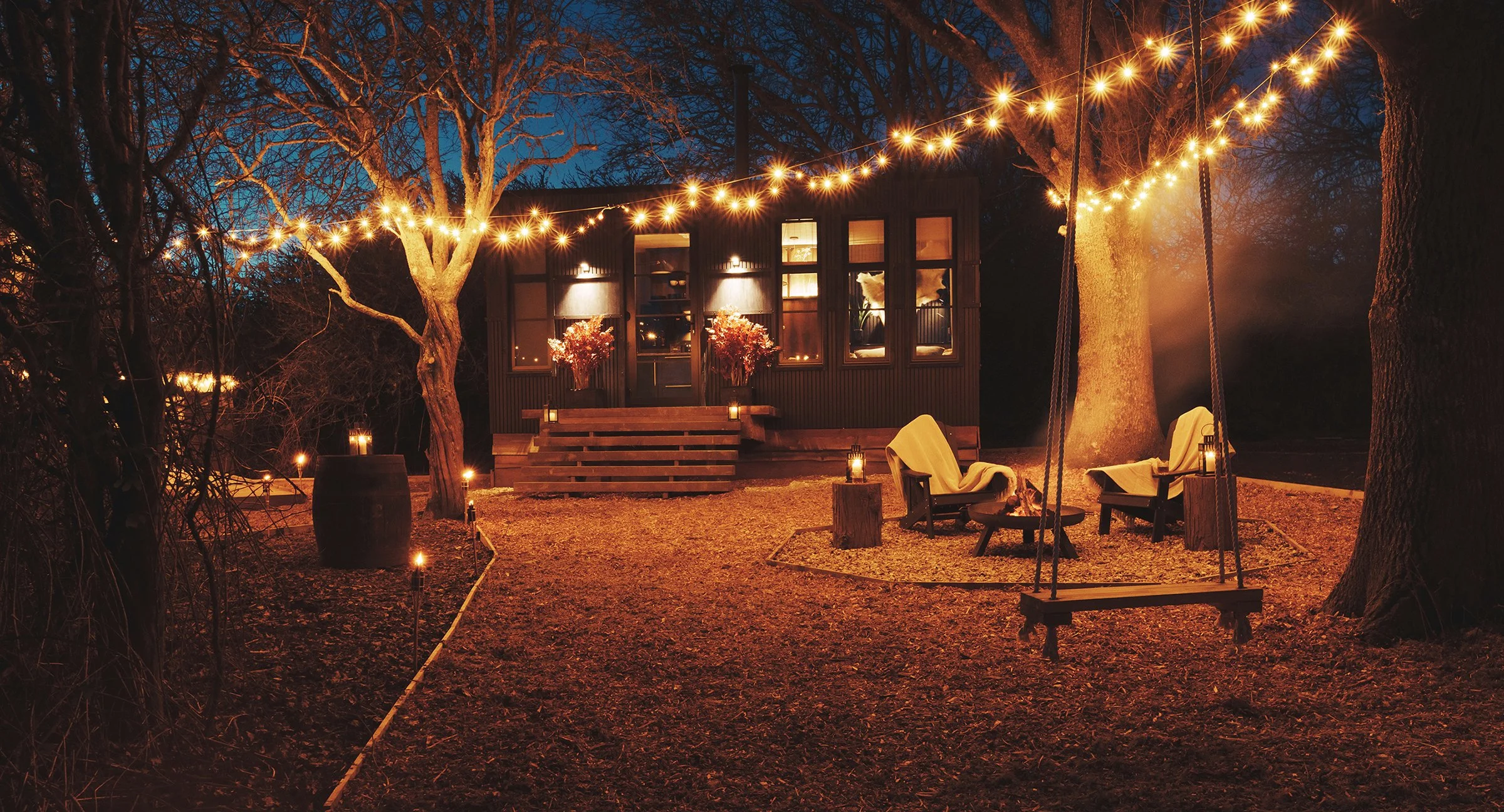 Festoon-lit venue and fire pit at dusk
