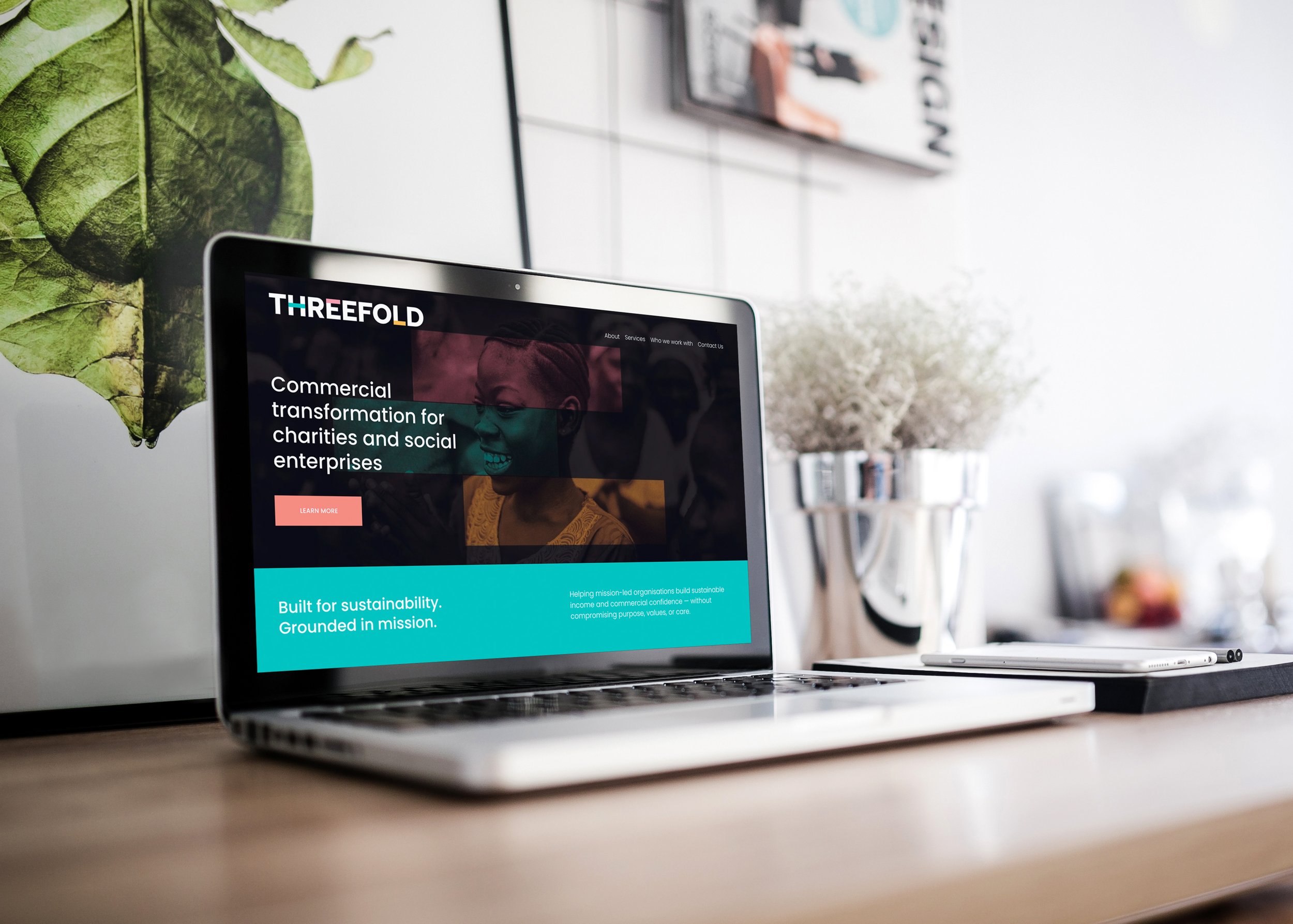 An iPad on a dark surface displaying a website for architectural design with a modern house and the words "LIVE BEAUTIFULLY".